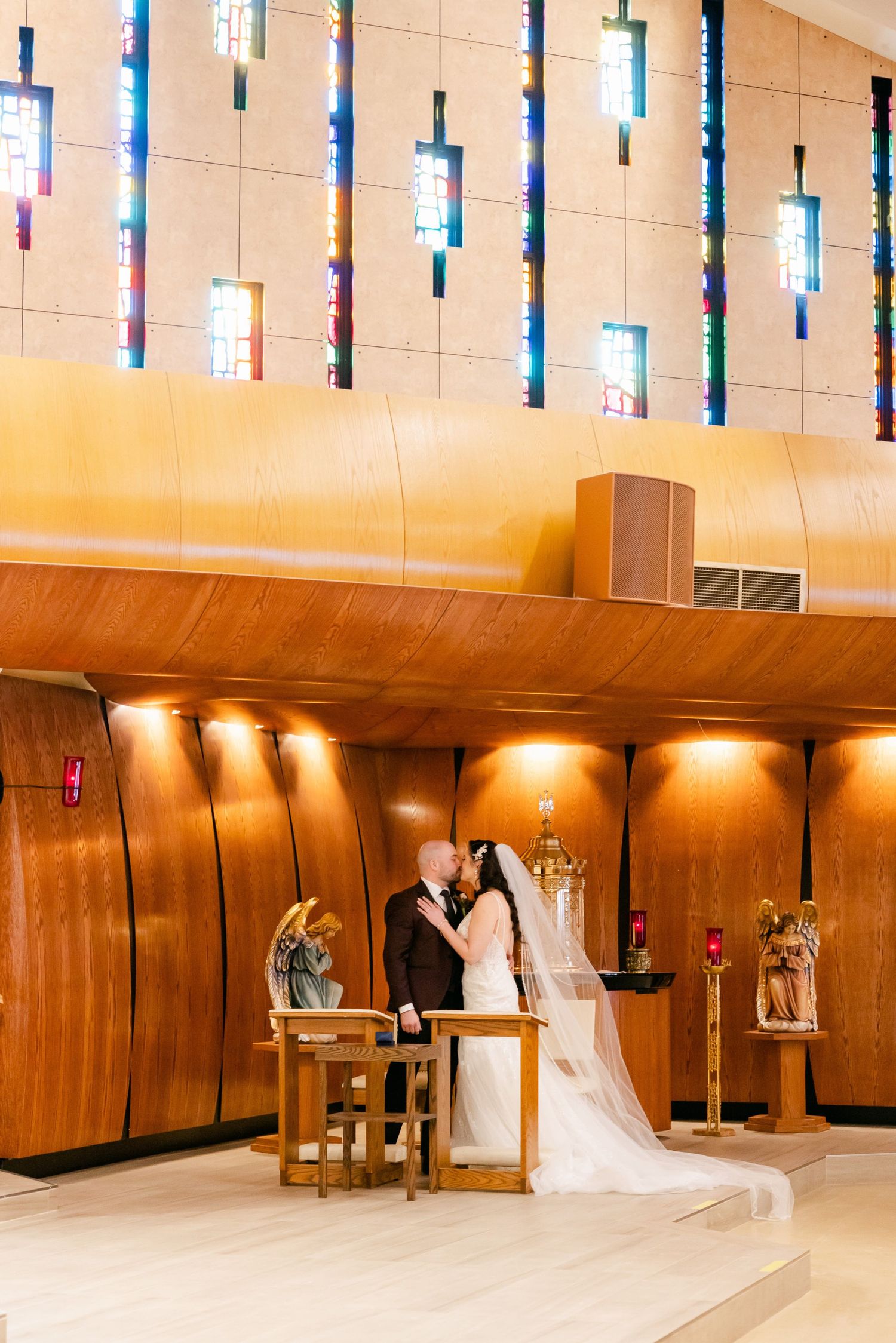 Modern church interior with colorful vertical windows and wooden paneling during wedding ceremony.