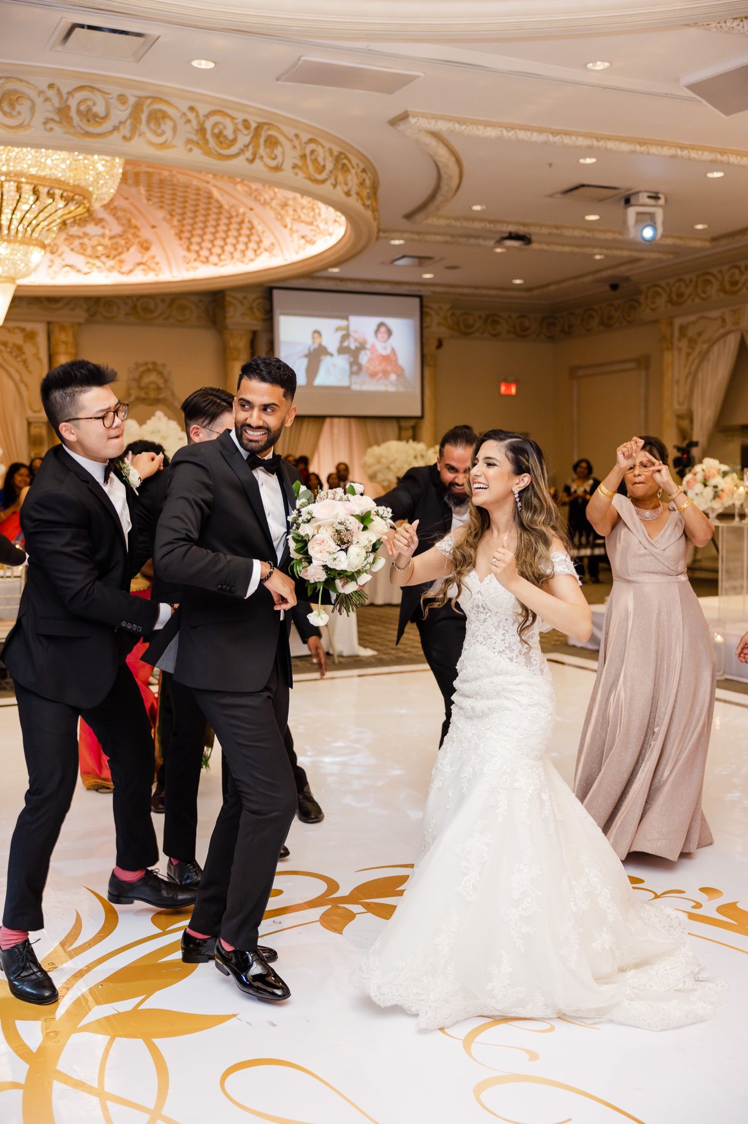 Wedding reception celebration with dancing guests in an ornate ballroom setting.