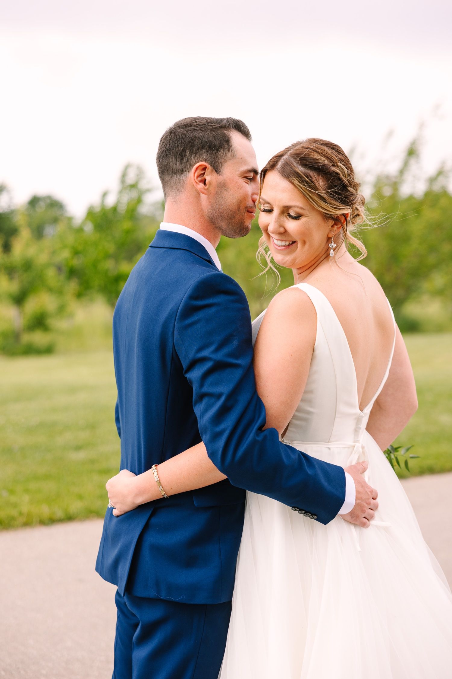 Wedding couple shares a romantic moment on a pathway surrounded by greenery.
