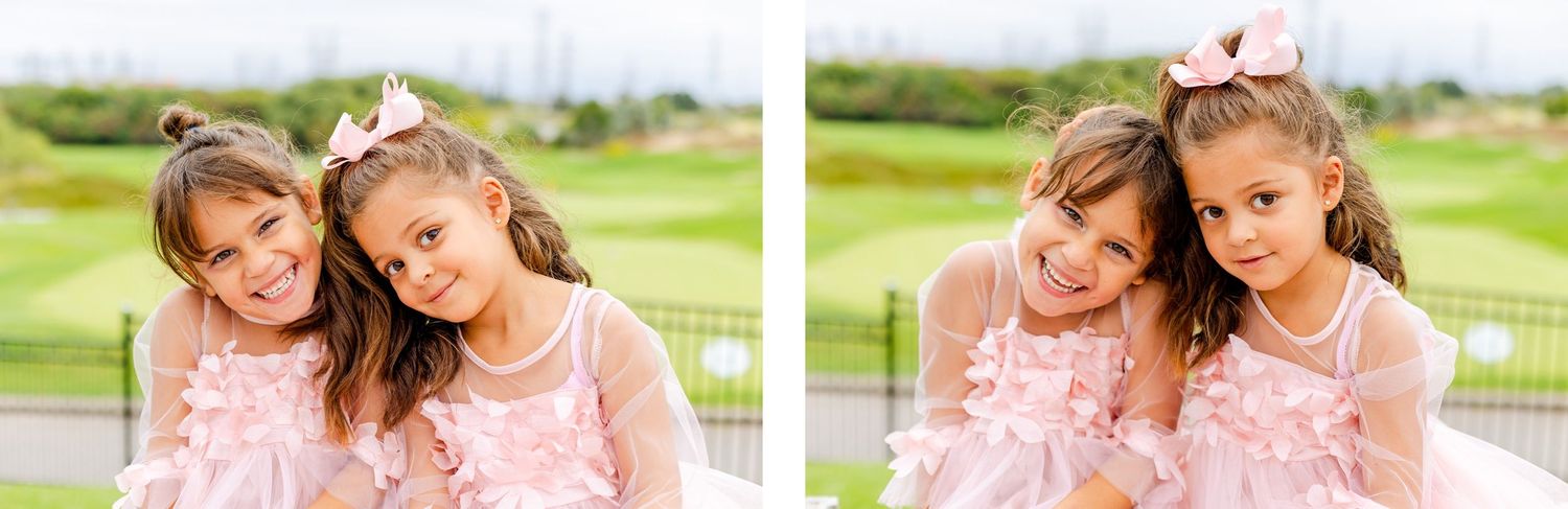 Two young girls in pink dresses pose together outdoors.