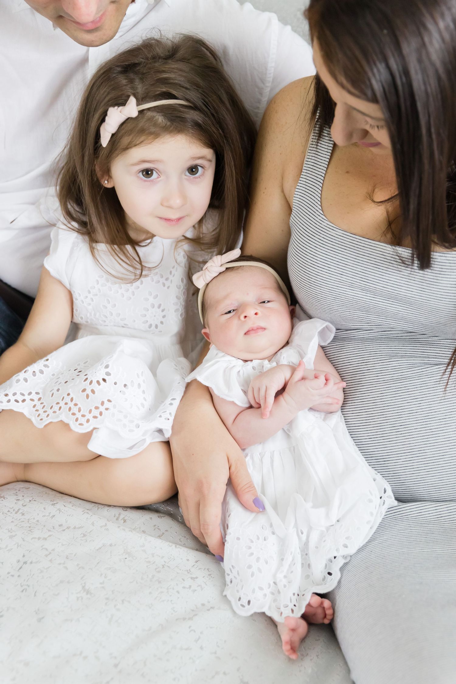 Family portrait featuring two children in white dresses with parents.