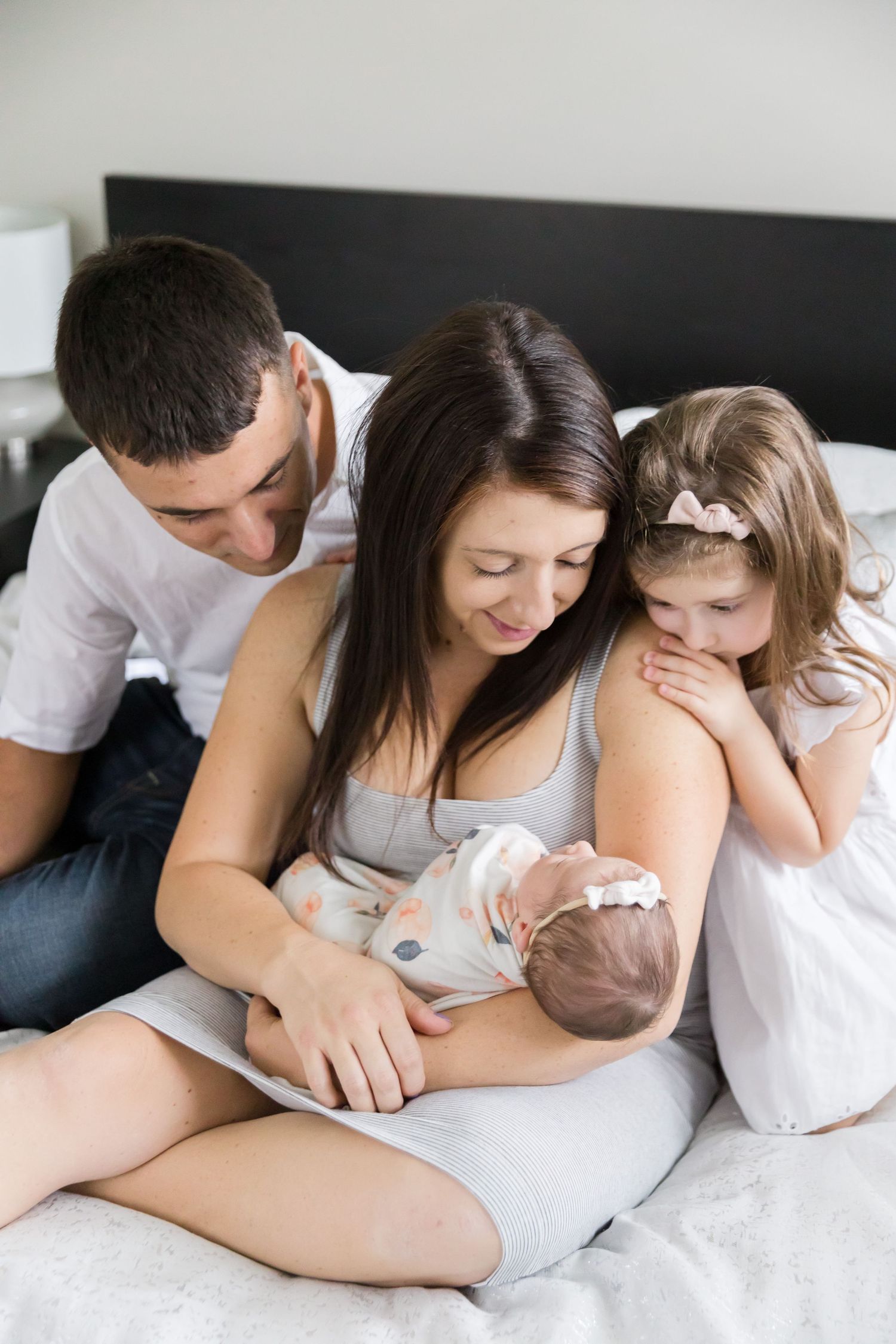 Family gathering on bed to bond with their newborn.