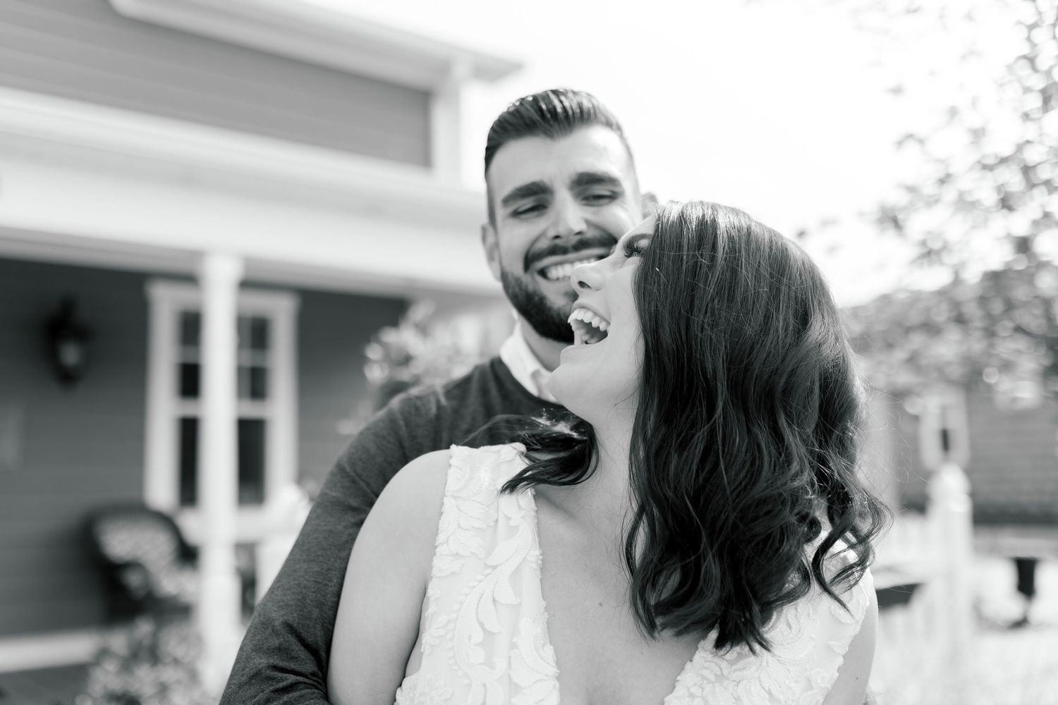 A black and white intimate portrait of a couple sharing a tender moment outdoors.