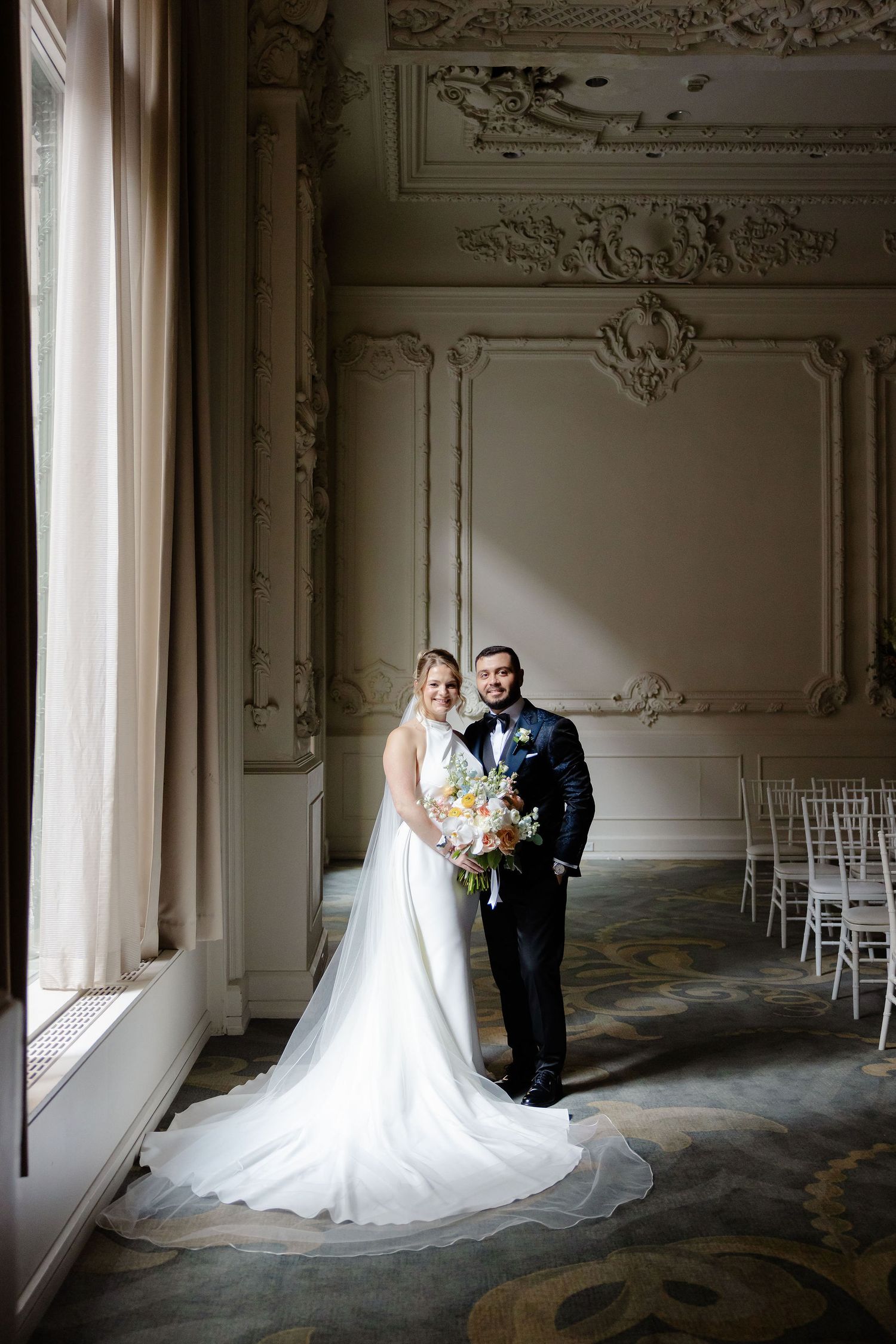 Elegant wedding portraits in an ornate room with decorative moldings and natural window light.