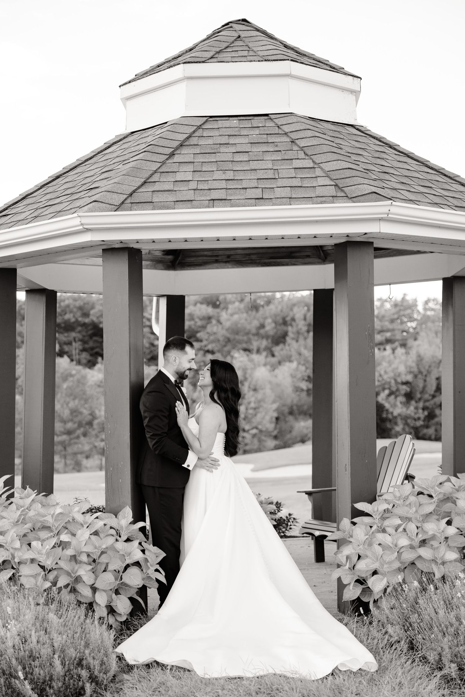 Black and white wedding photo of a couple sharing a moment in an elegant garden gazebo.