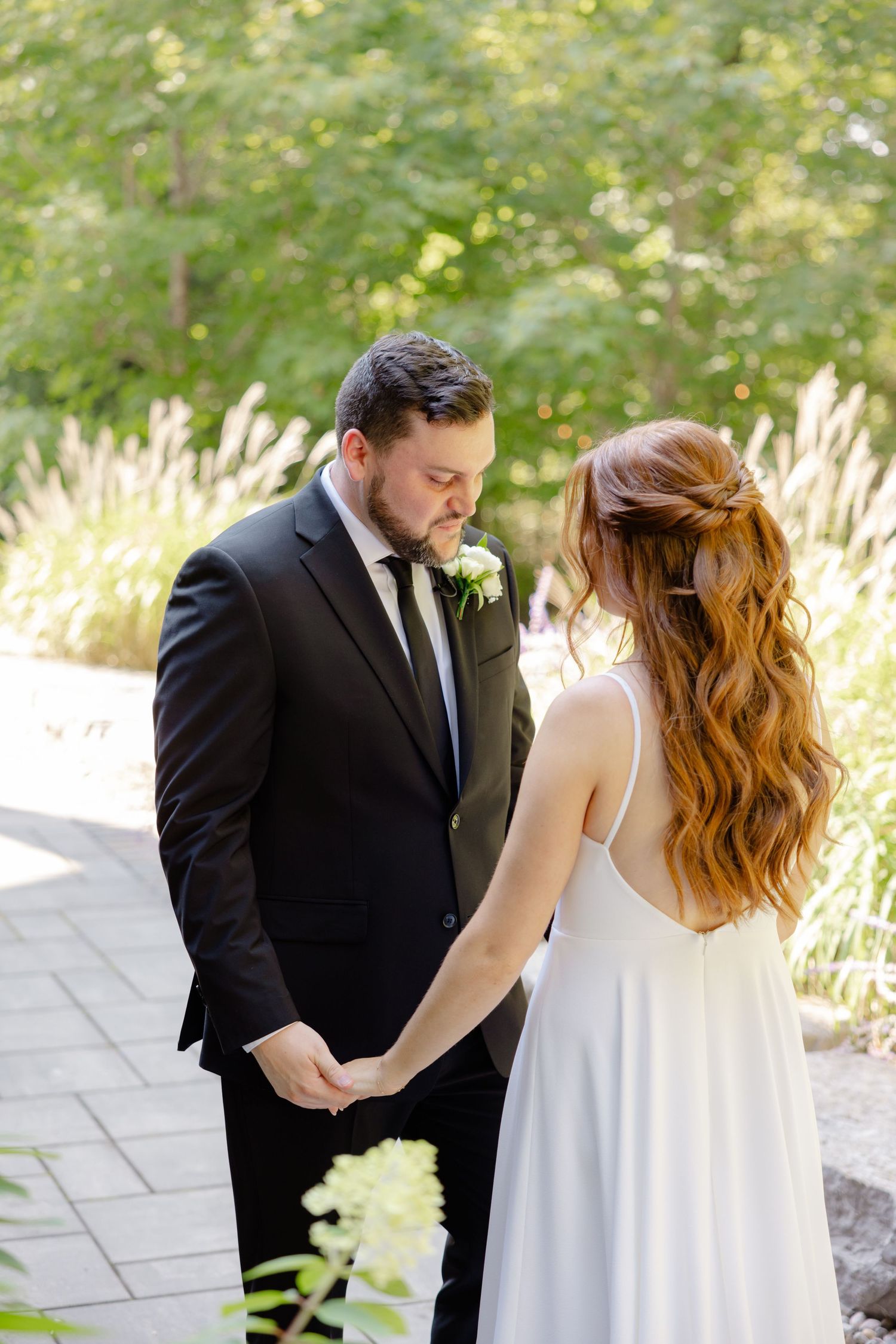 Beautiful wedding moment captured on a garden path with ornamental grasses and greenery.