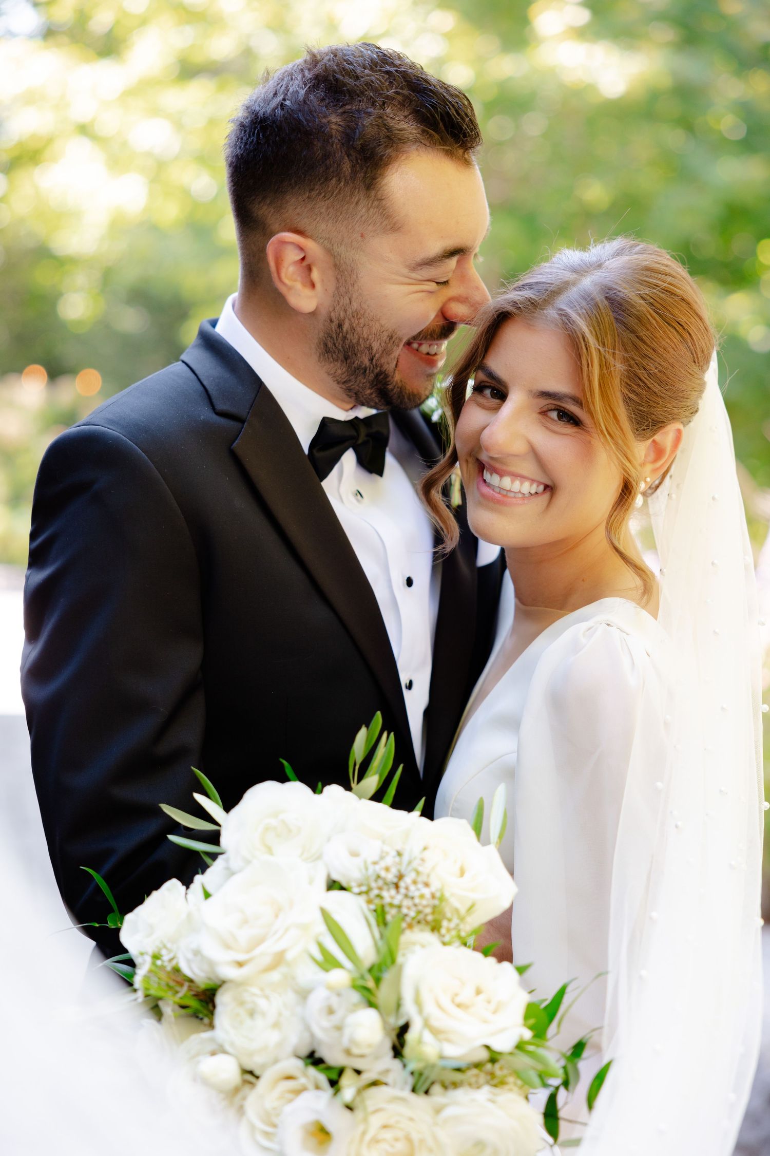 Intimate close-up of newlyweds sharing a tender moment with white roses.