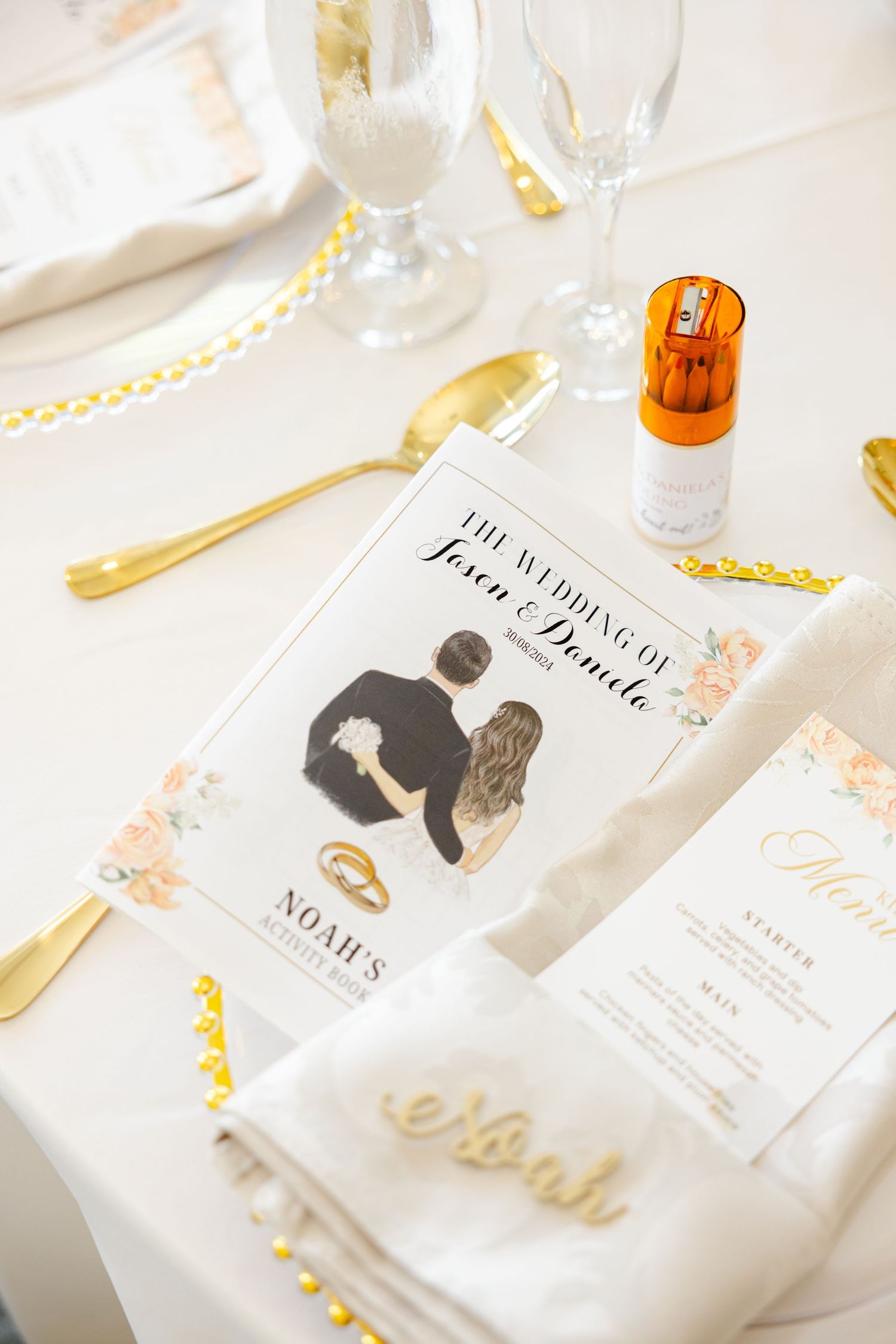Wedding stationery and place settings featuring gold cutlery and personalized menus.