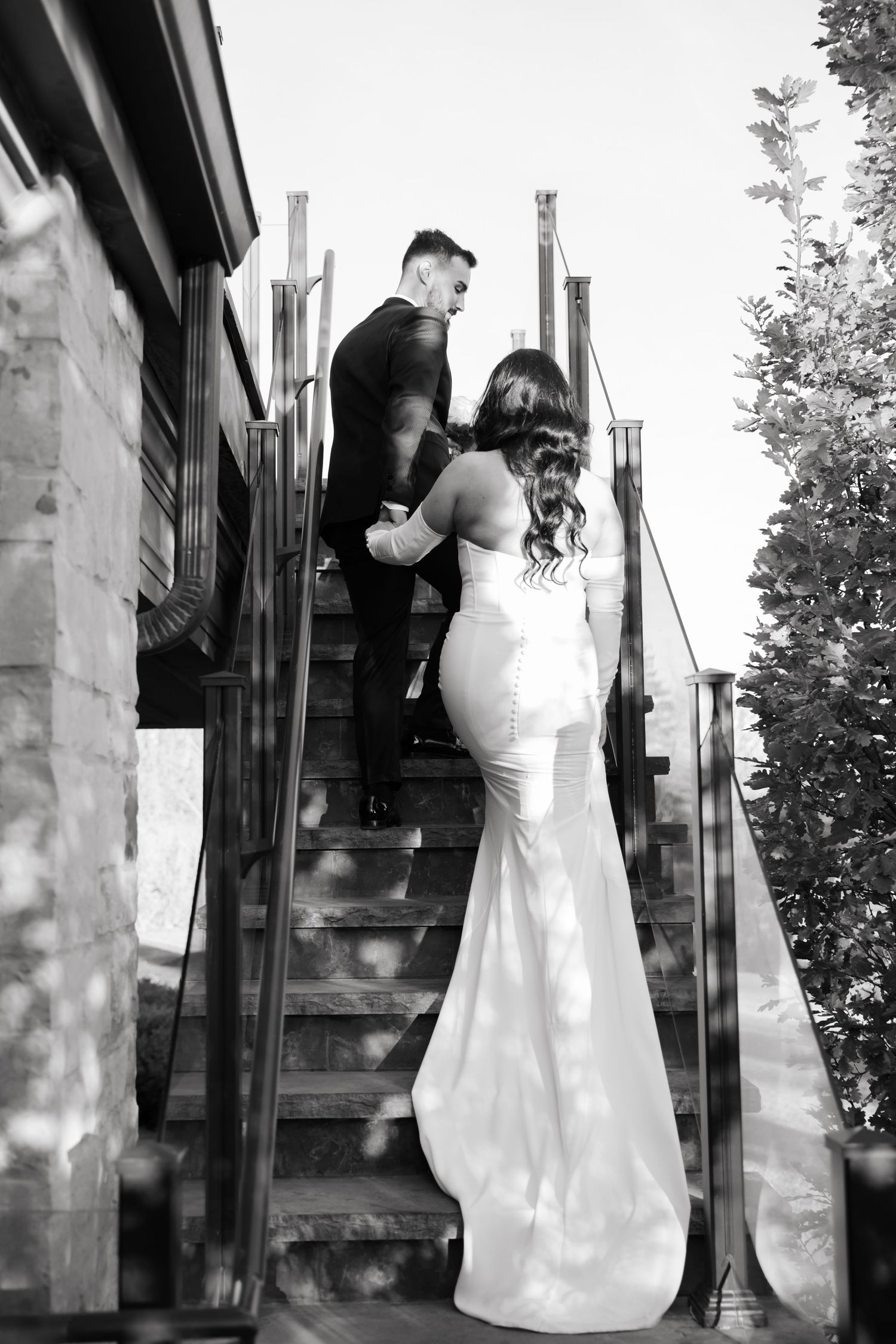 Dramatic black and white shot of wedding couple climbing modern metal staircase.
