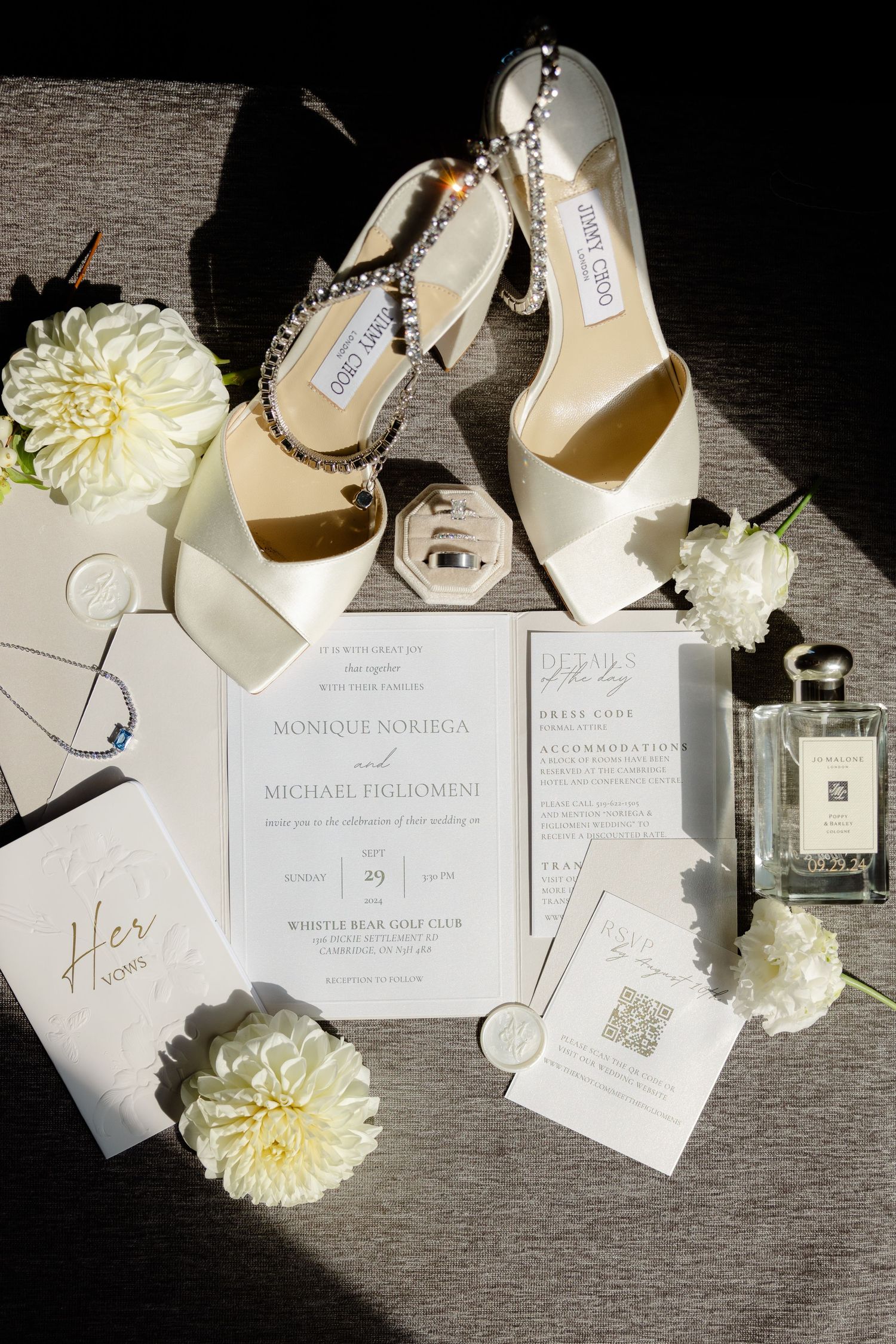 Wedding details flat lay featuring white Jimmy Choo shoes, invitations and floral accents.
