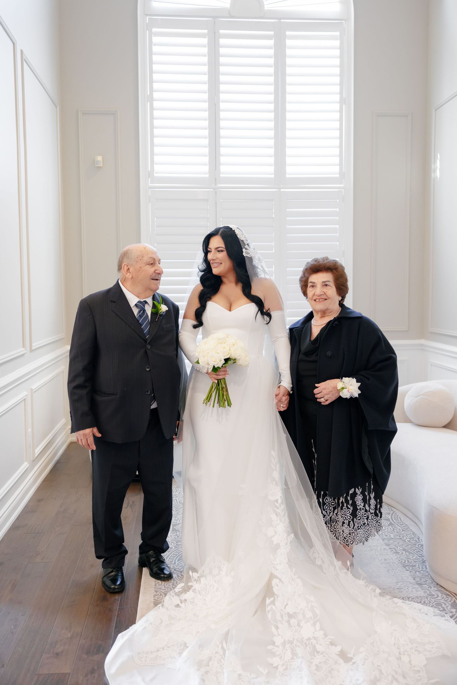 Beautiful wedding photo capturing special moment in bright white room with shuttered window.