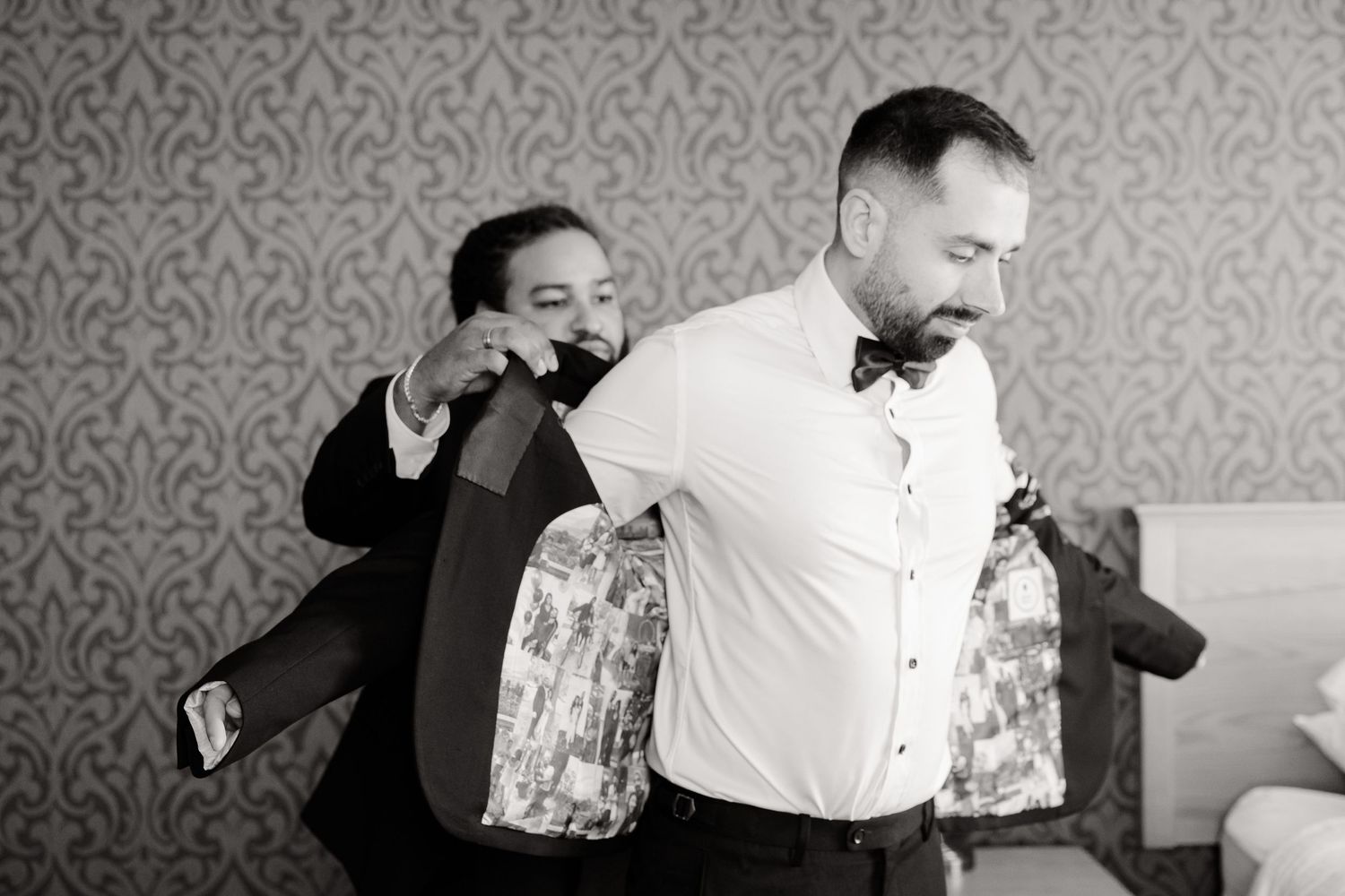 Black and white candid shot of wedding preparation moments with two people getting dressed.