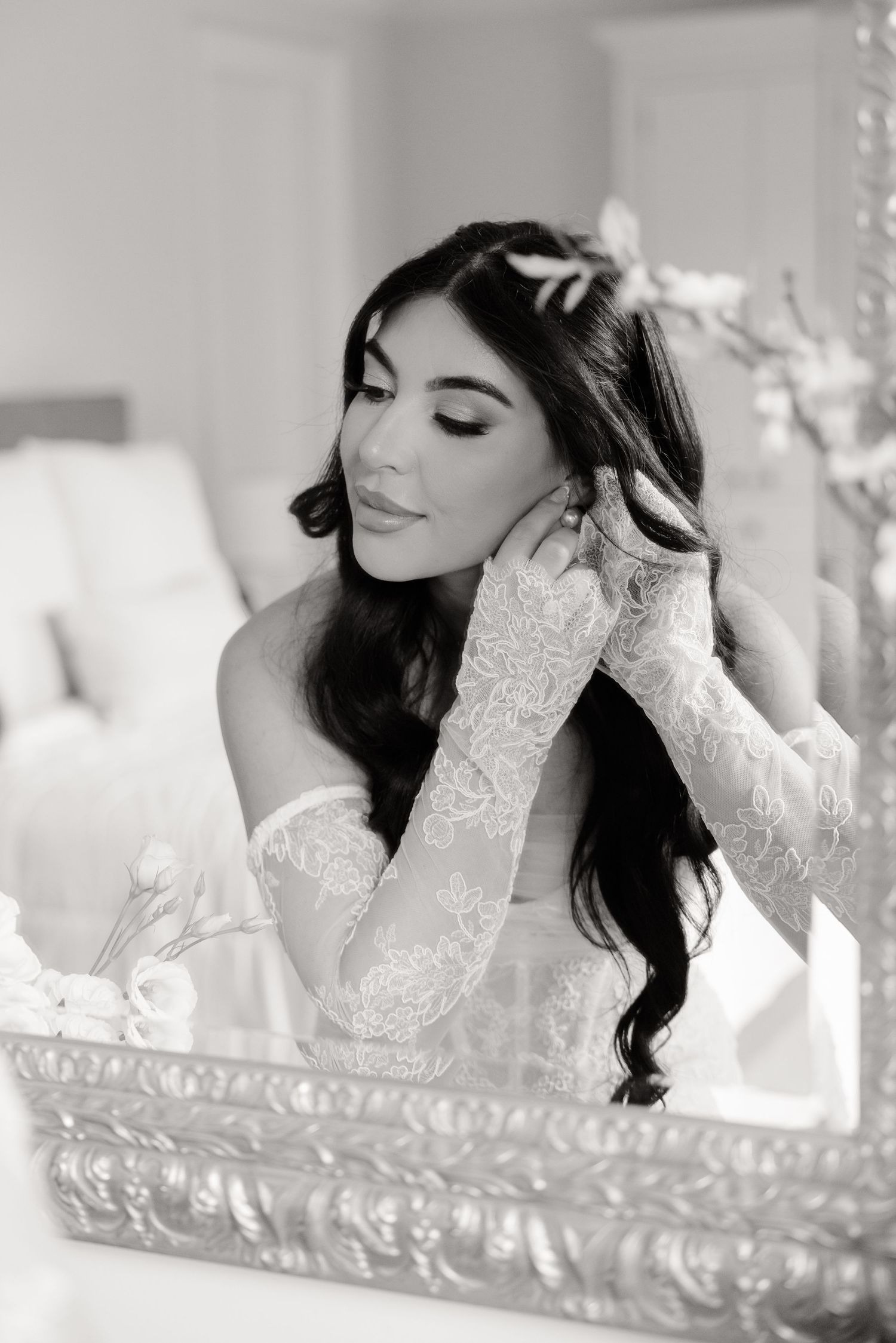 A bride in a white lace wedding gown lies elegantly on a vintage-style settee during a boudoir photo session.