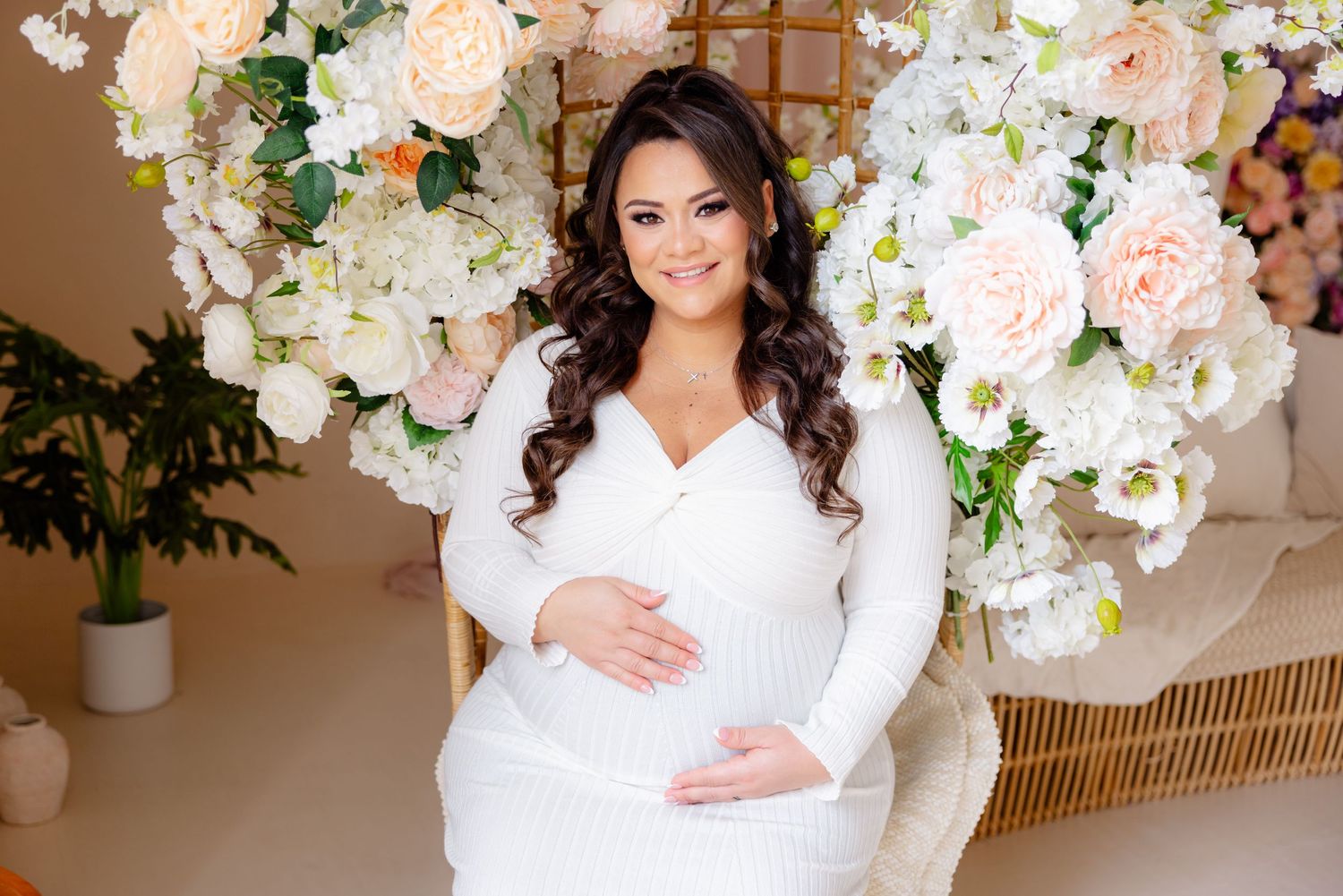 A maternity photo with floral decorations featuring pink and white flowers against a warm backdrop.