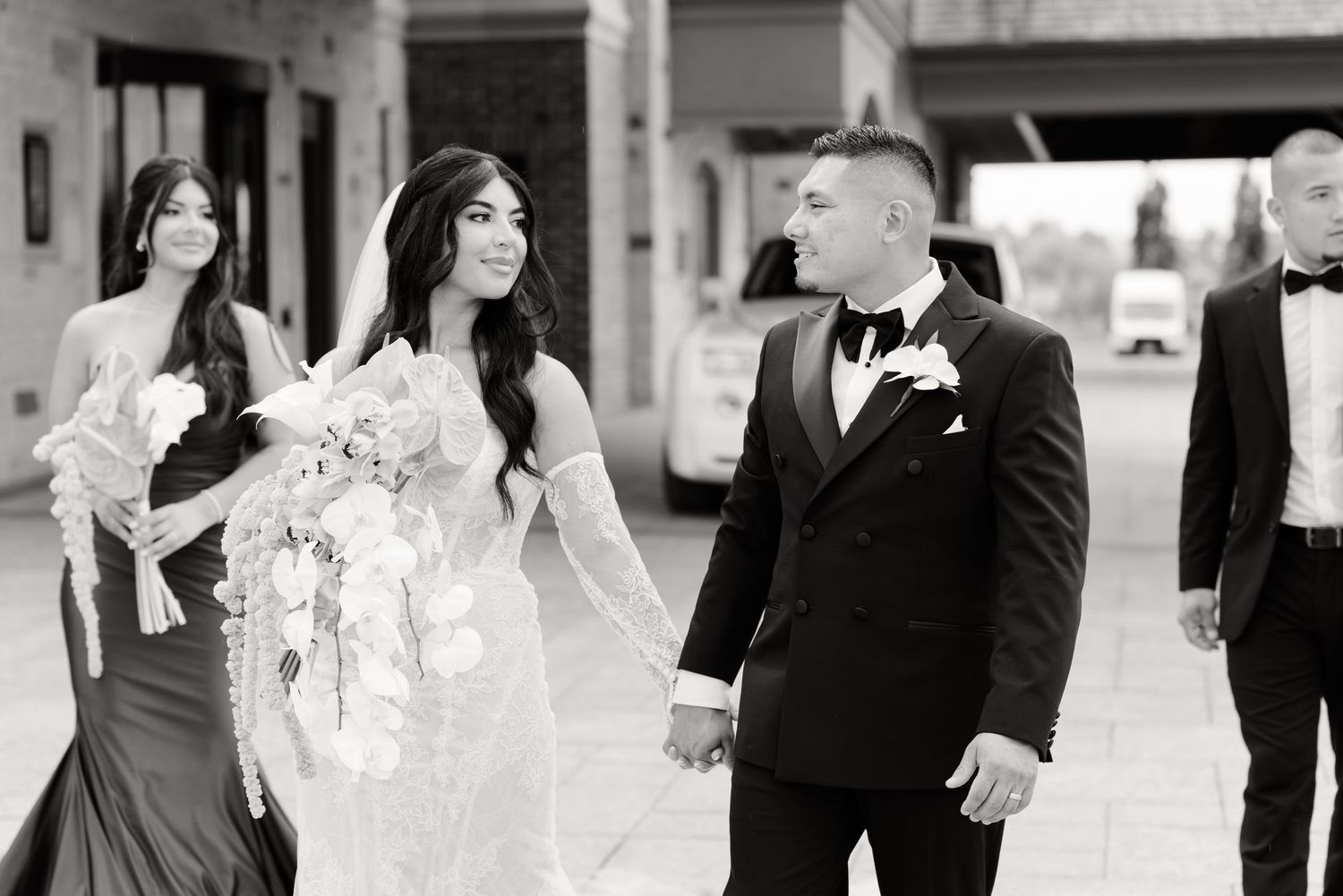 Wedding party members dressed in black and white walk and celebrate together in elegant formal attire.