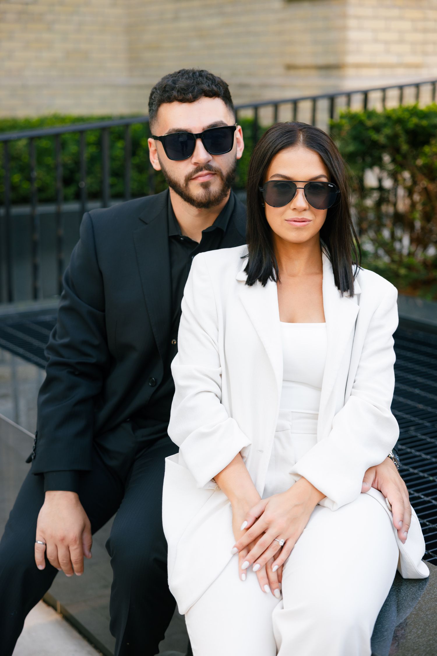 Fashionable duo in black and white attire pose outside luxury Chanel store.