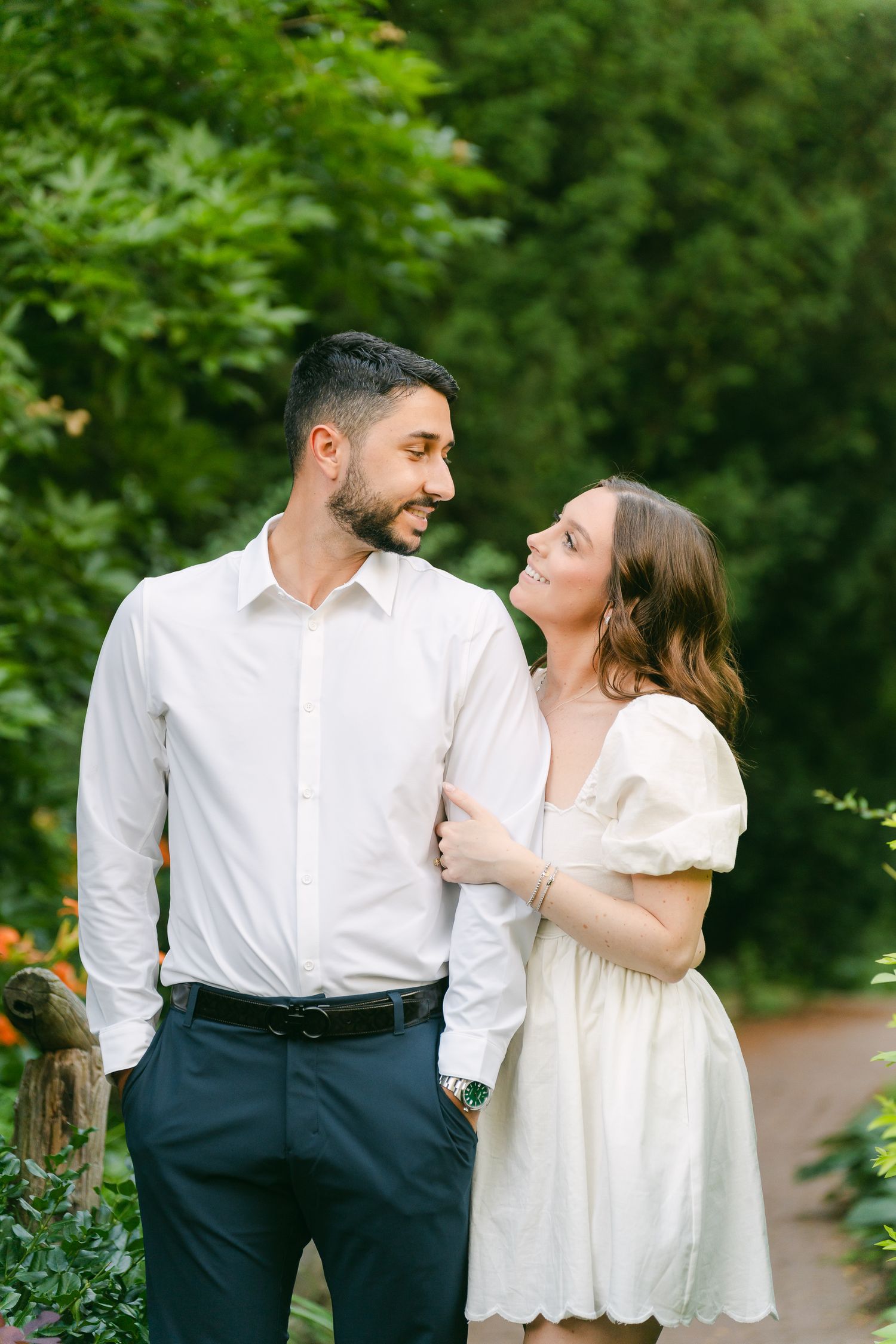 Romantic couple sharing a tender moment while standing on garden path among blooming flowers.