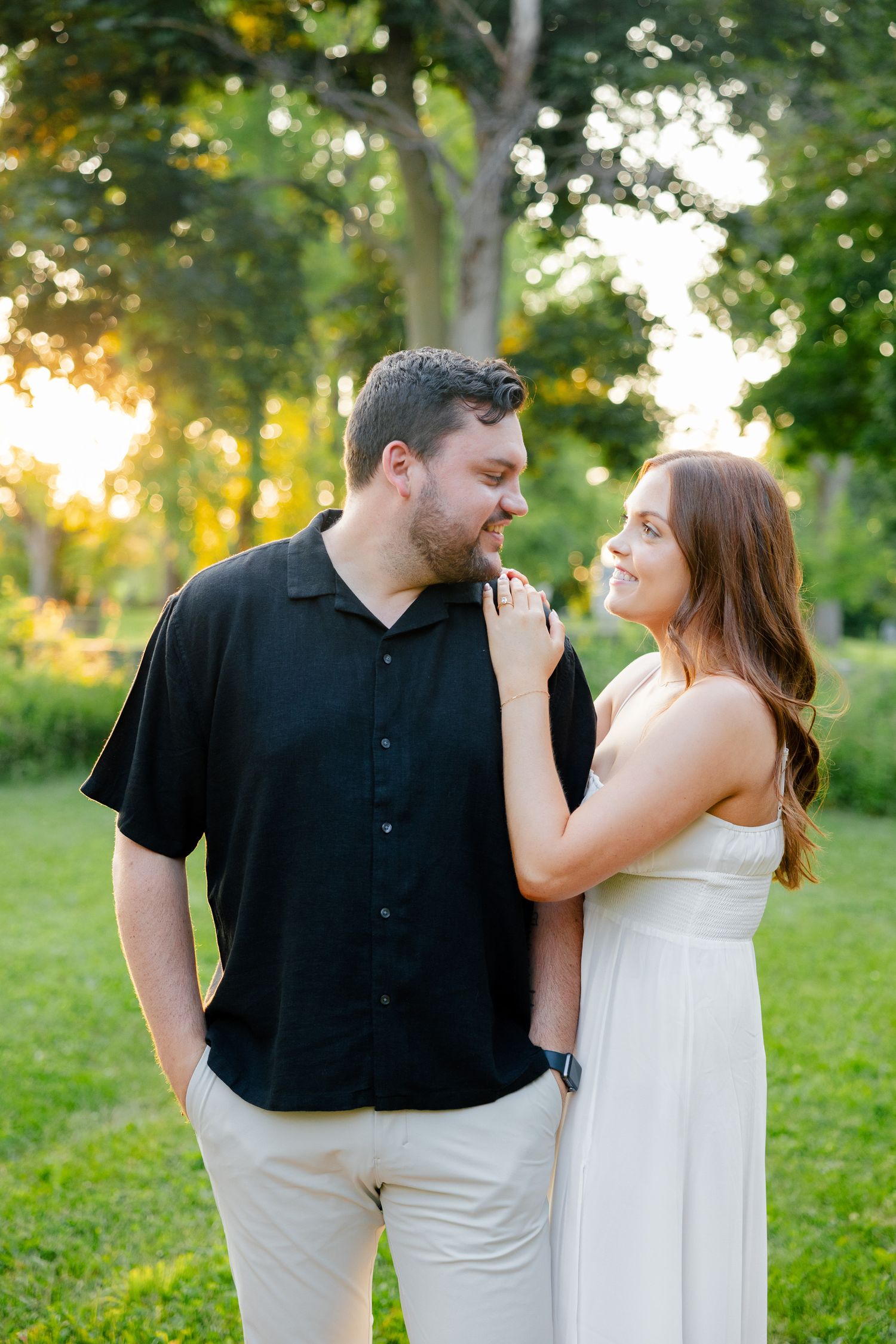 Romantic couple in coordinated black and white outfits share an intimate moment in a sunlit park.