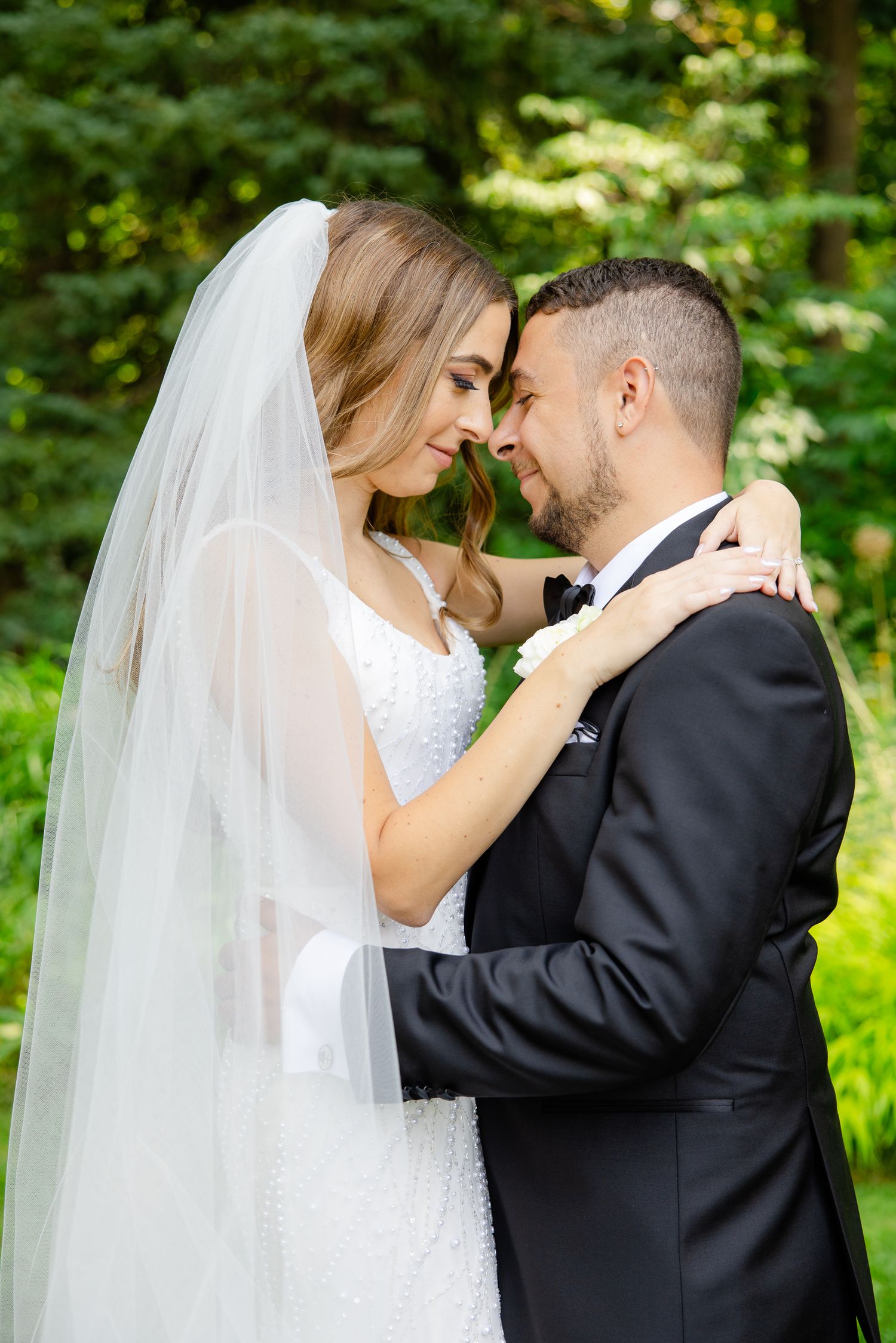 Intimate close-up of wedding couple sharing tender moment outdoors with flowing veil.