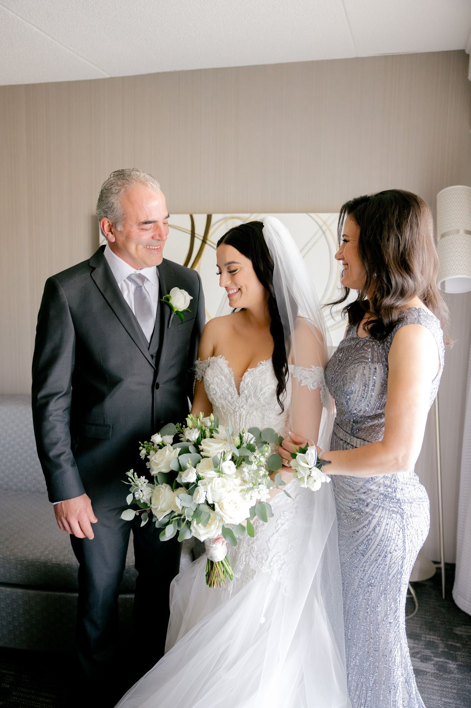 Wedding party members share an intimate moment while admiring a beautiful bouquet of white flowers.
