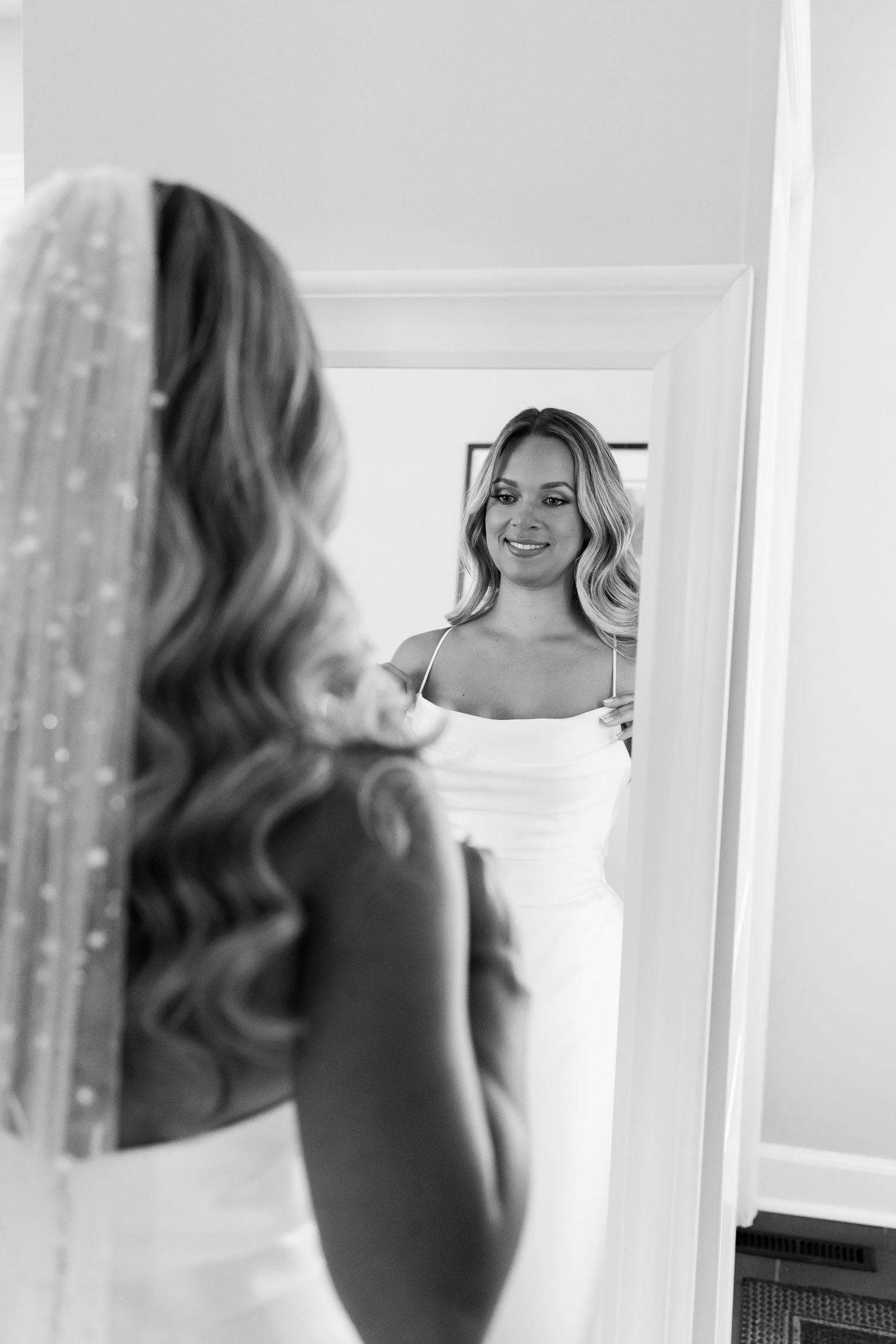 Black and white image showing a reflection in a mirror during wedding preparations.