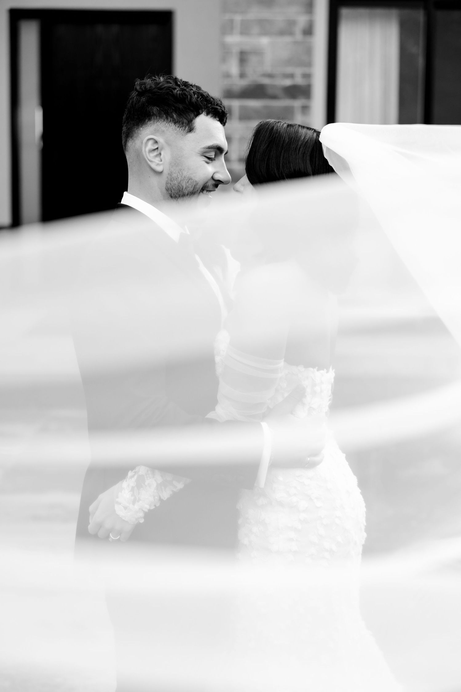 A dreamy black and white wedding photo with the veil creating an artistic blur effect.