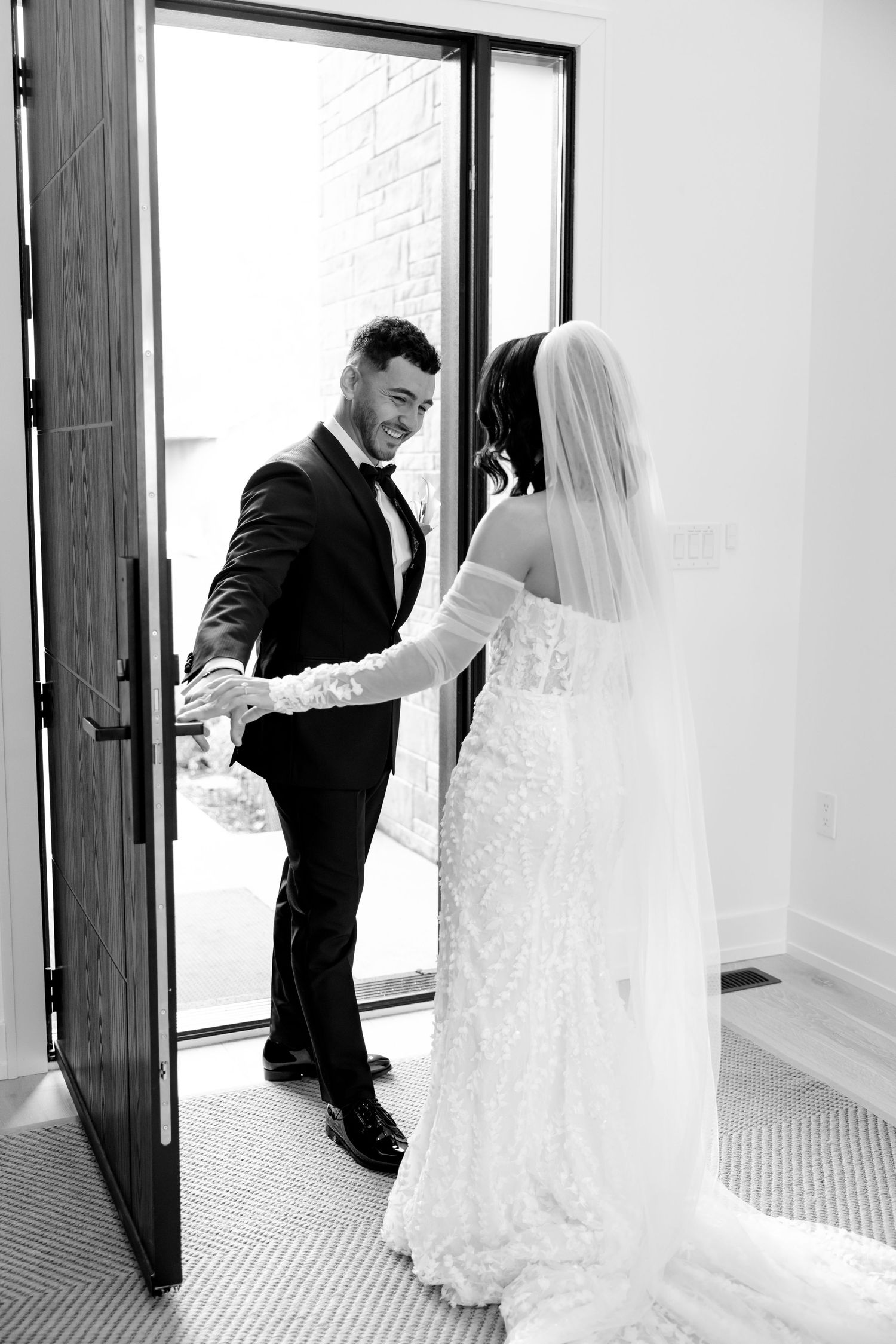 A candid black and white photo of newlyweds during their first look moment.