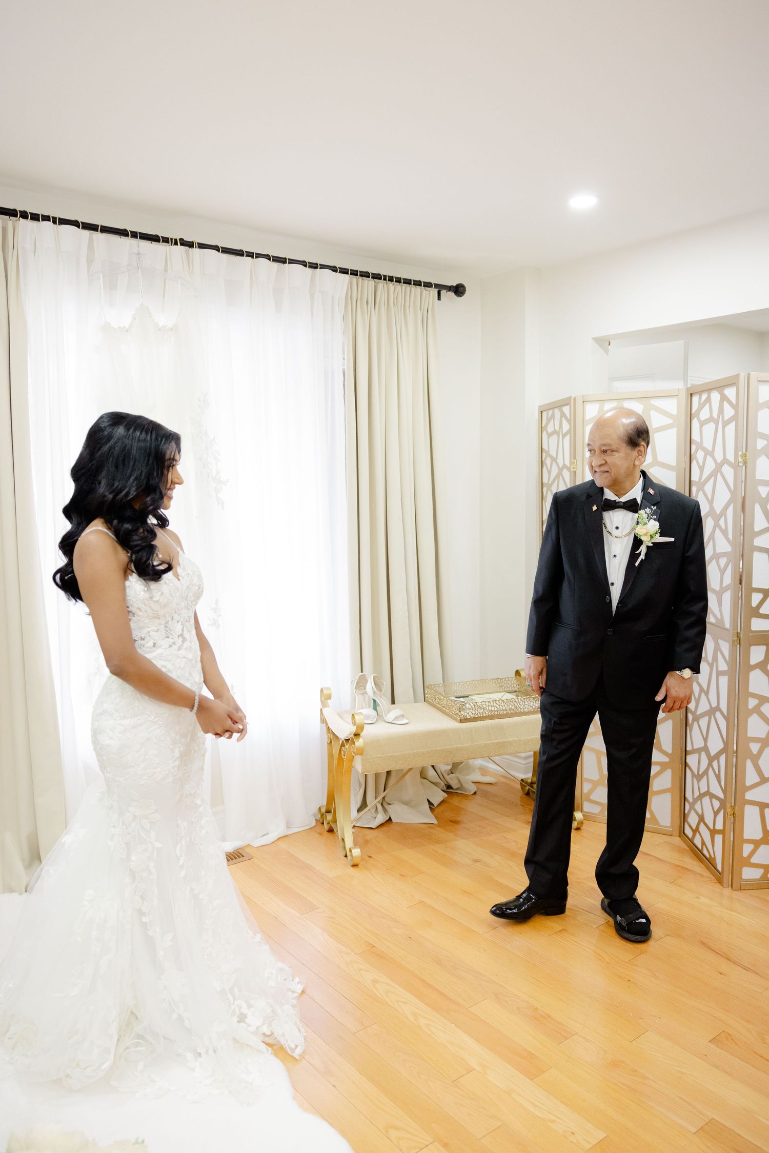 Emotional wedding day moment captured in a bright room with elegant decor and hardwood floors.