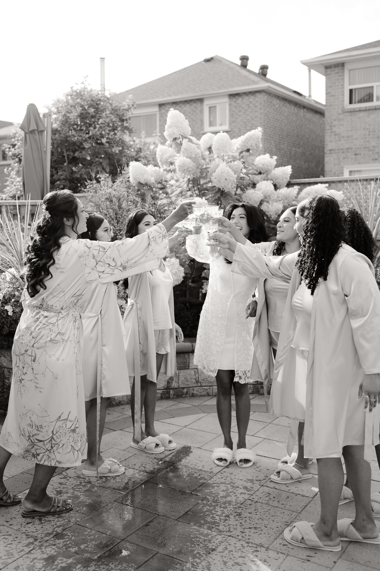 Black and white photo of celebratory toast on patio with matching robes.