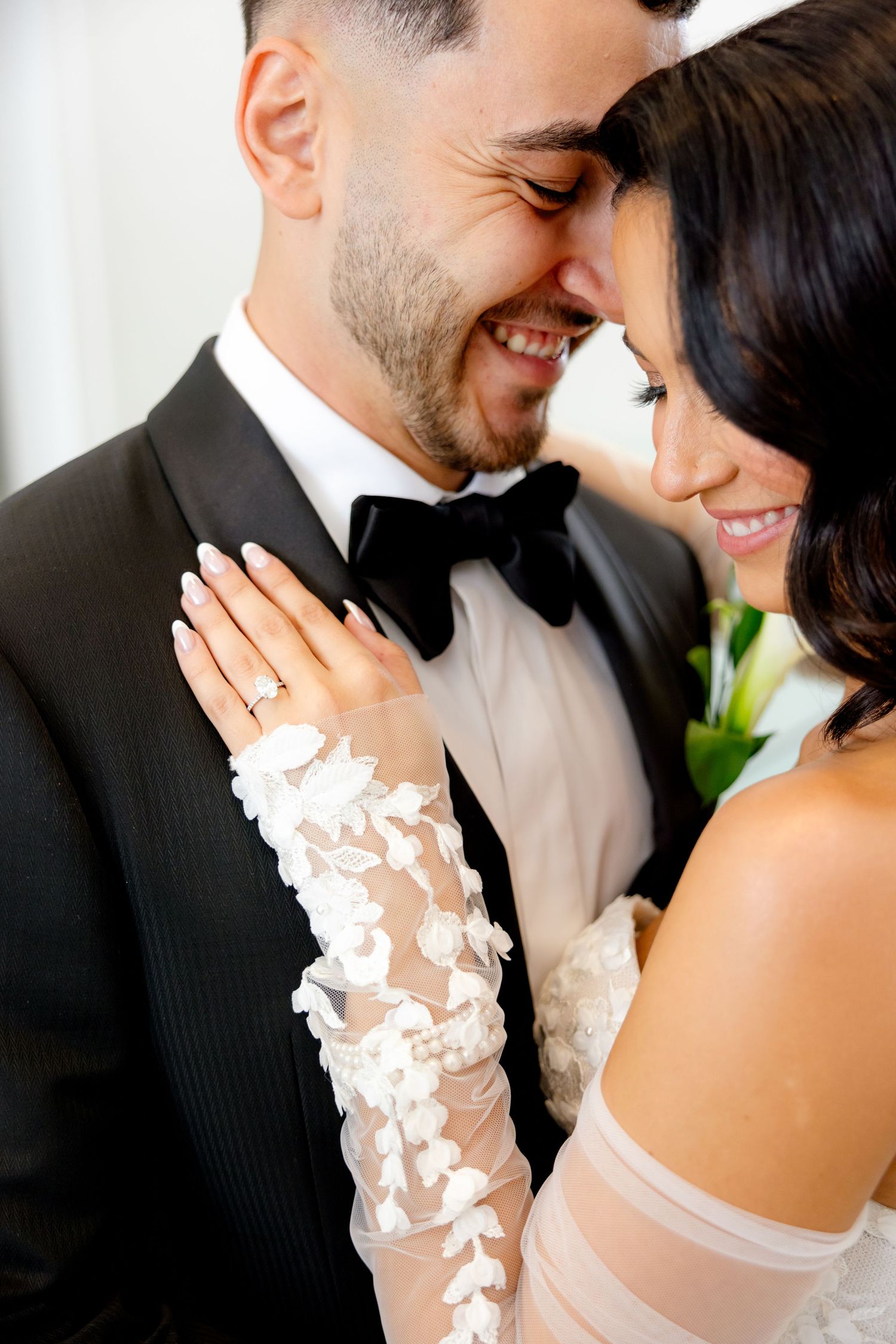 A close-up capture of a loving moment between newlyweds showing the bride's detailed lace sleeve.