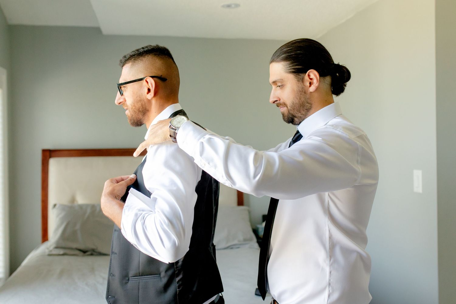 Two people helping each other get dressed in formal wear.