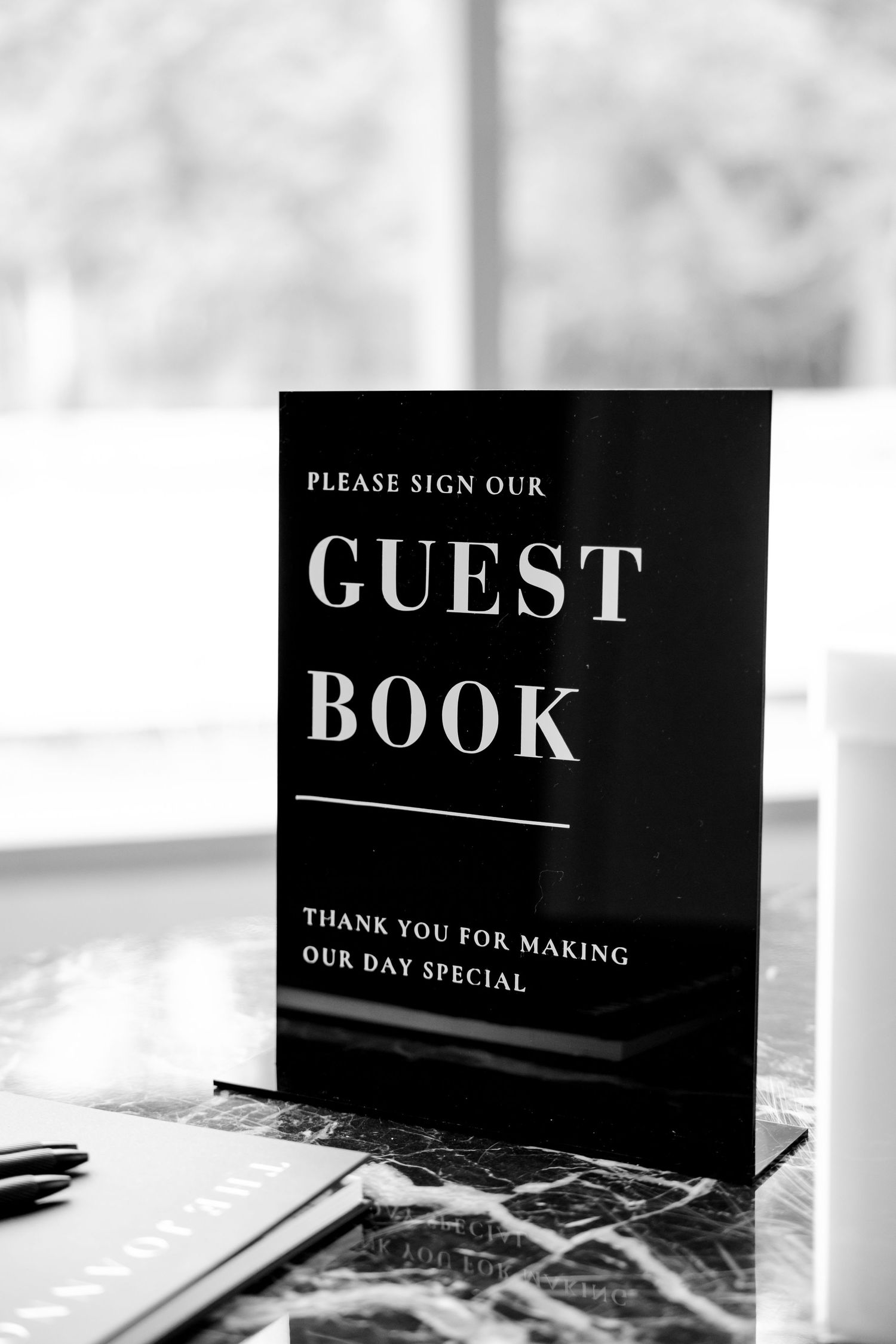 Black and white guest book sign with pen ready for wedding attendees.