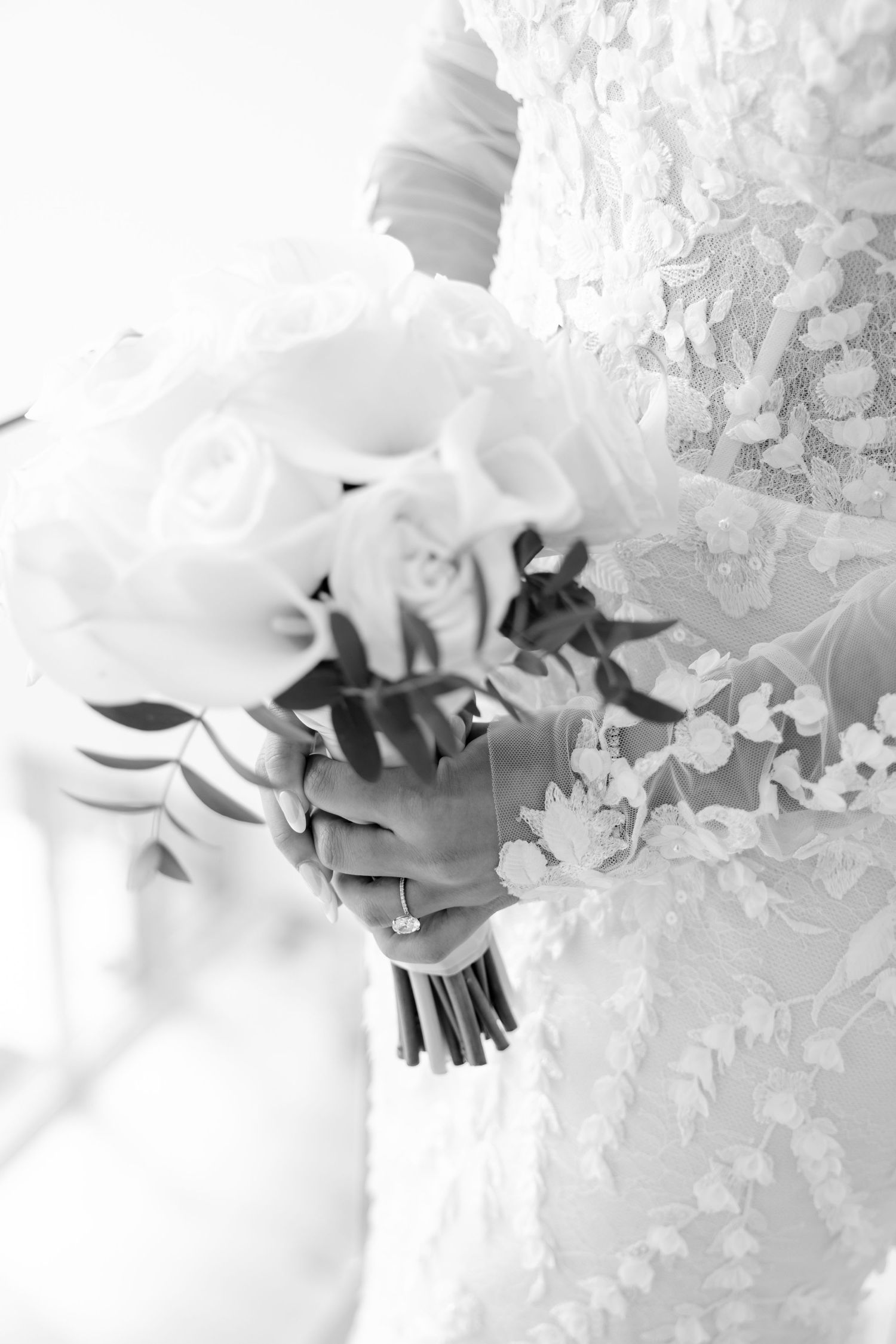 Black and white detail shot of wedding bouquet against lace dress texture.