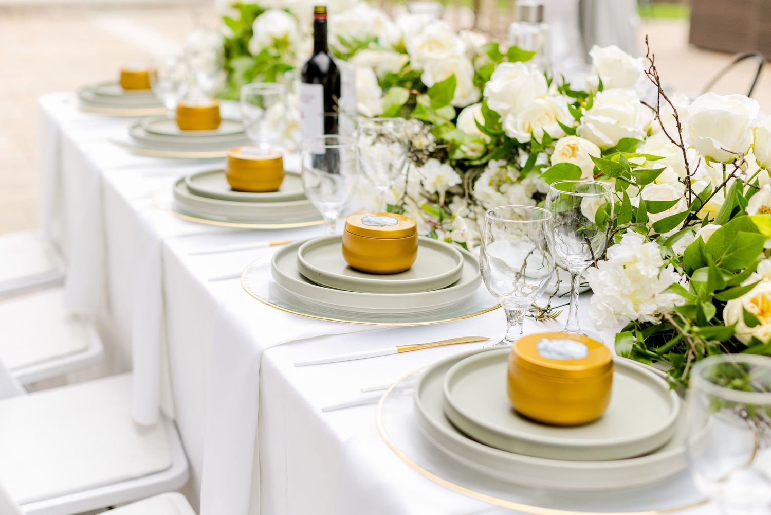 Elegant table setting with gold chargers, white linens, and fresh floral centerpieces for an upscale event.