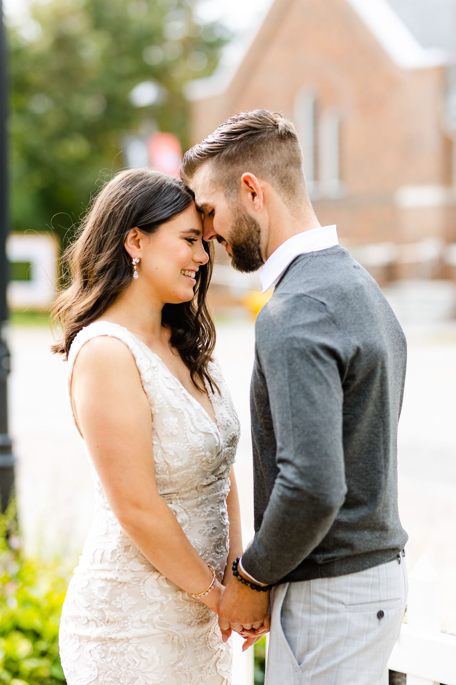 Romantic moment captured between couple in formal wear with brick building backdrop.