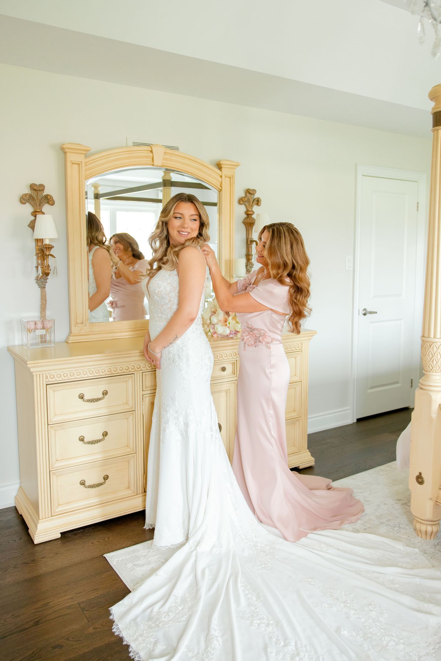 Beautiful wedding preparation scene with cream vanity mirror and flowing white gown.