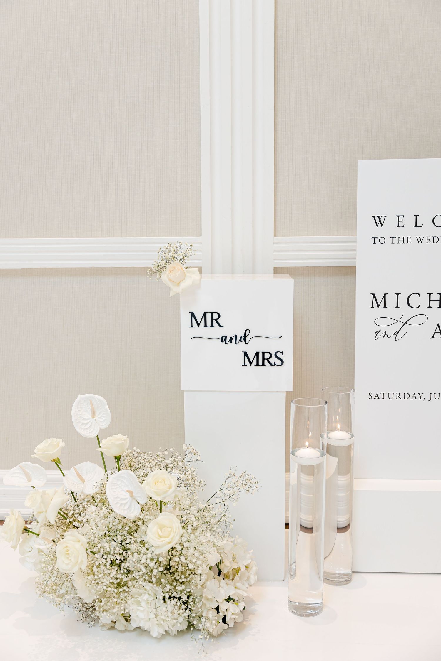 Minimalist wedding decor featuring Mr and Mrs sign with white roses and candles.