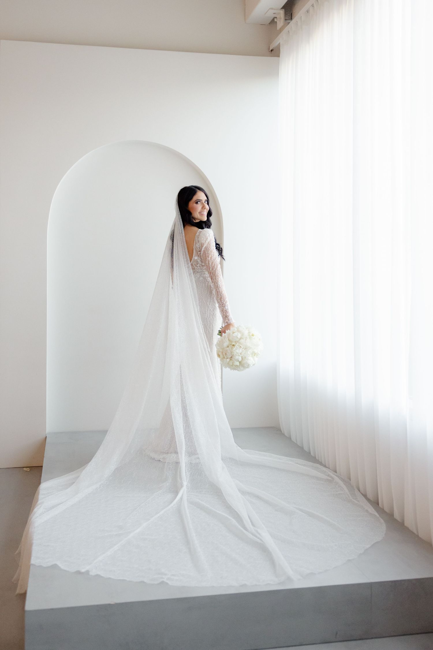 Dramatic bridal portrait showcasing intricate lace gown and cathedral length veil.