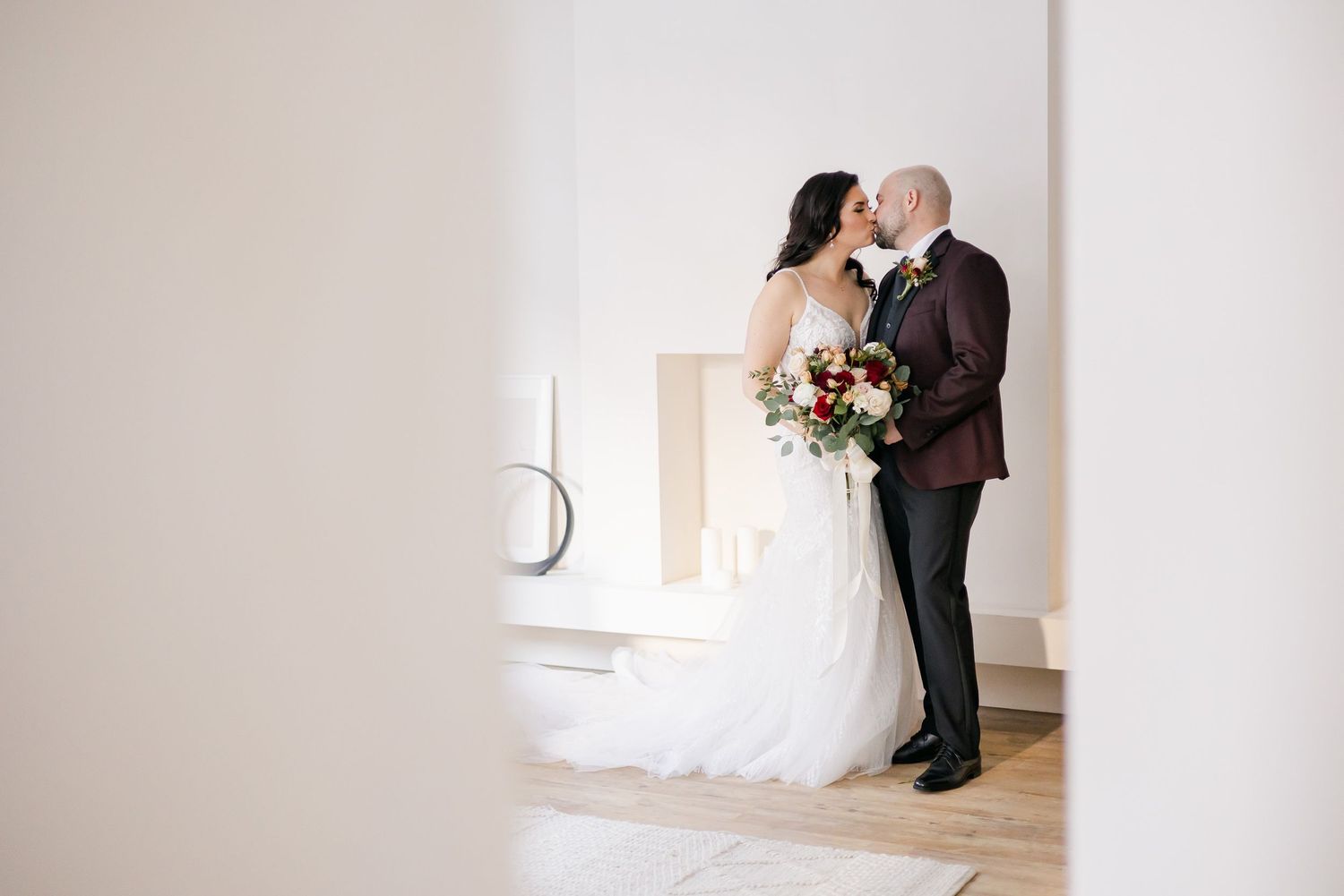 Artistic wedding photo capturing an intimate moment in front of white minimalist backdrop.
