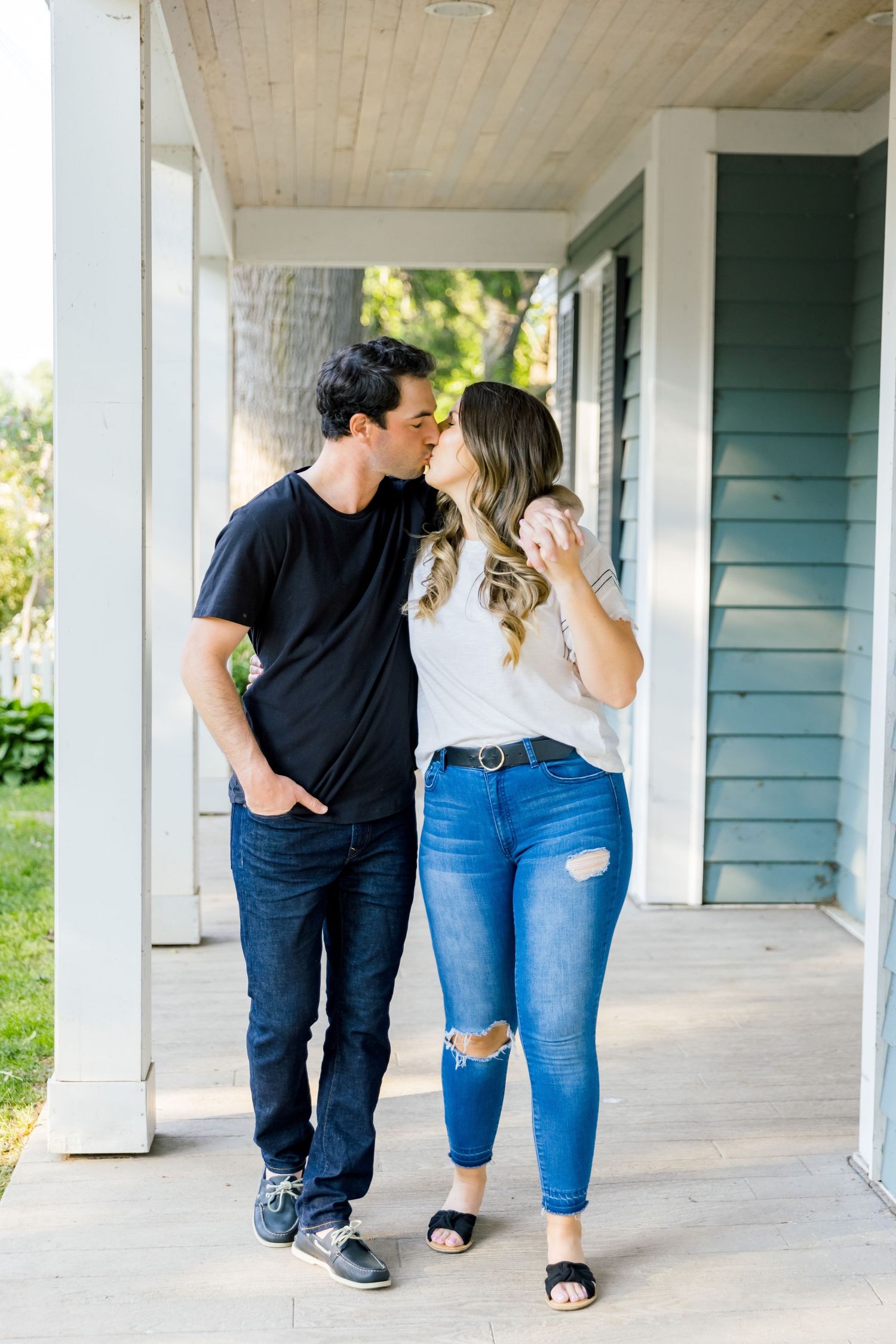 A romantic moment between a couple walking along a covered porch of a green house.