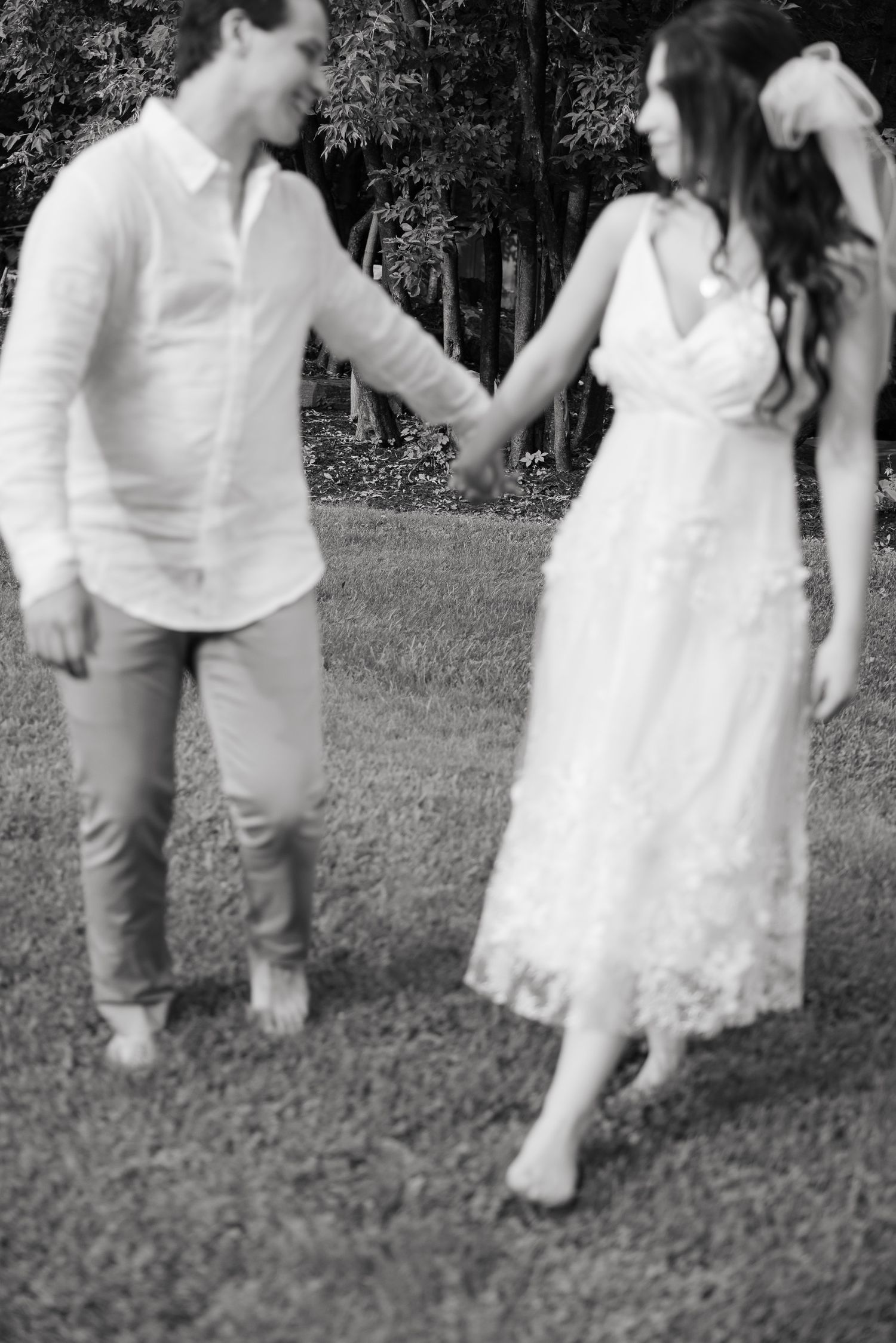 A black and white image of newlyweds dancing barefoot in a garden.
