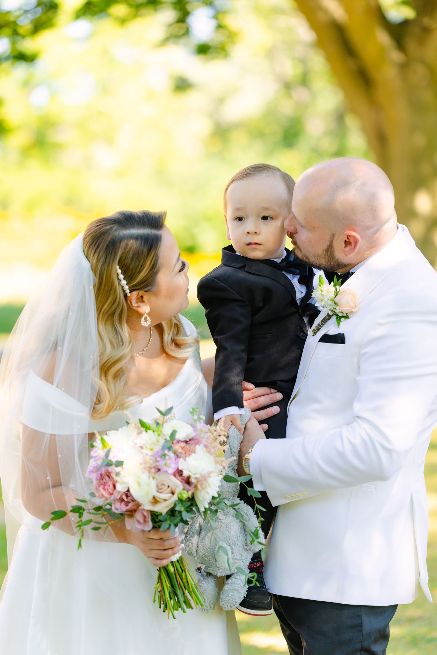 Beautiful wedding family portrait in garden setting with formal attire and floral bouquet.