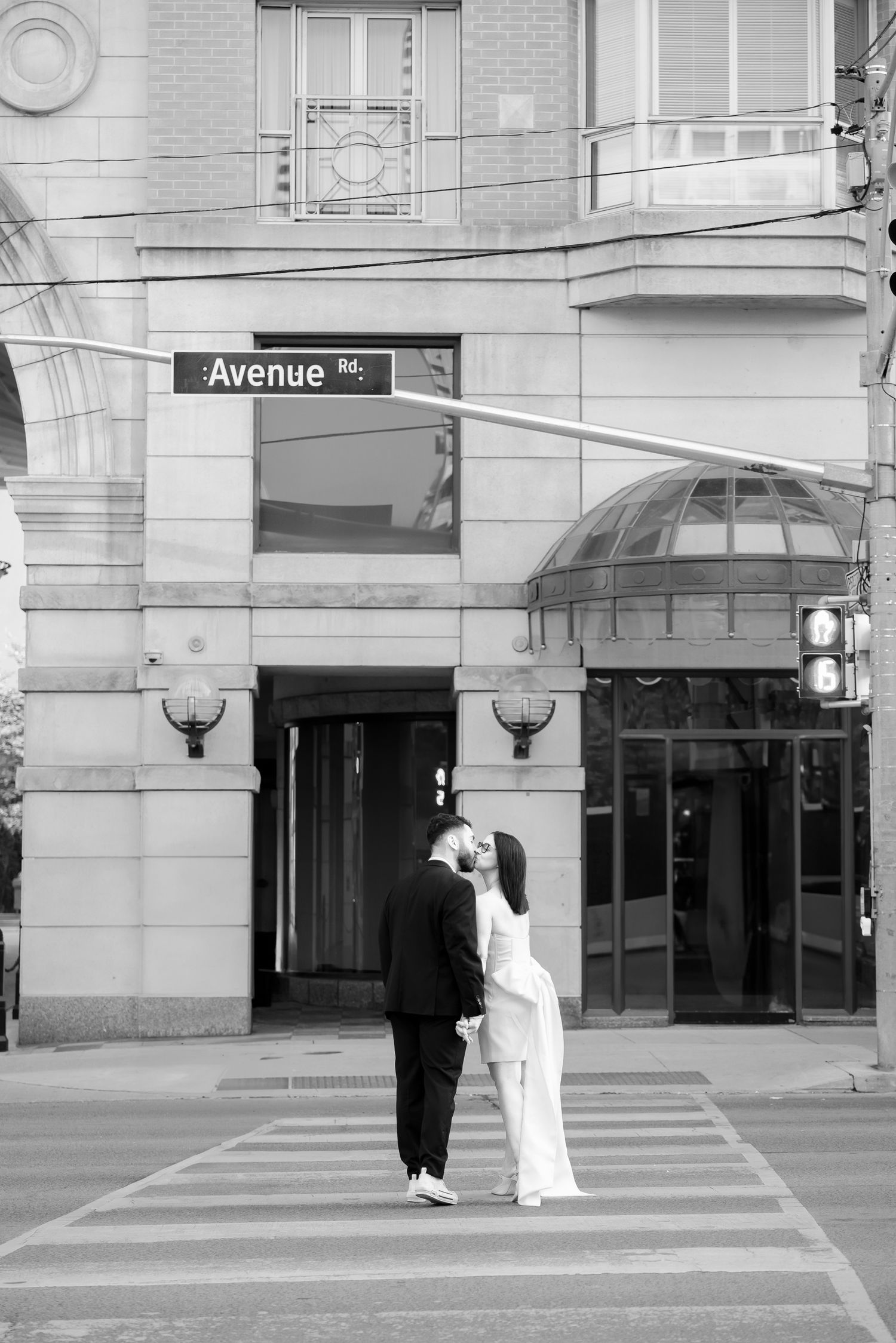 A romantic moment between a couple in formal wear on a city crosswalk.