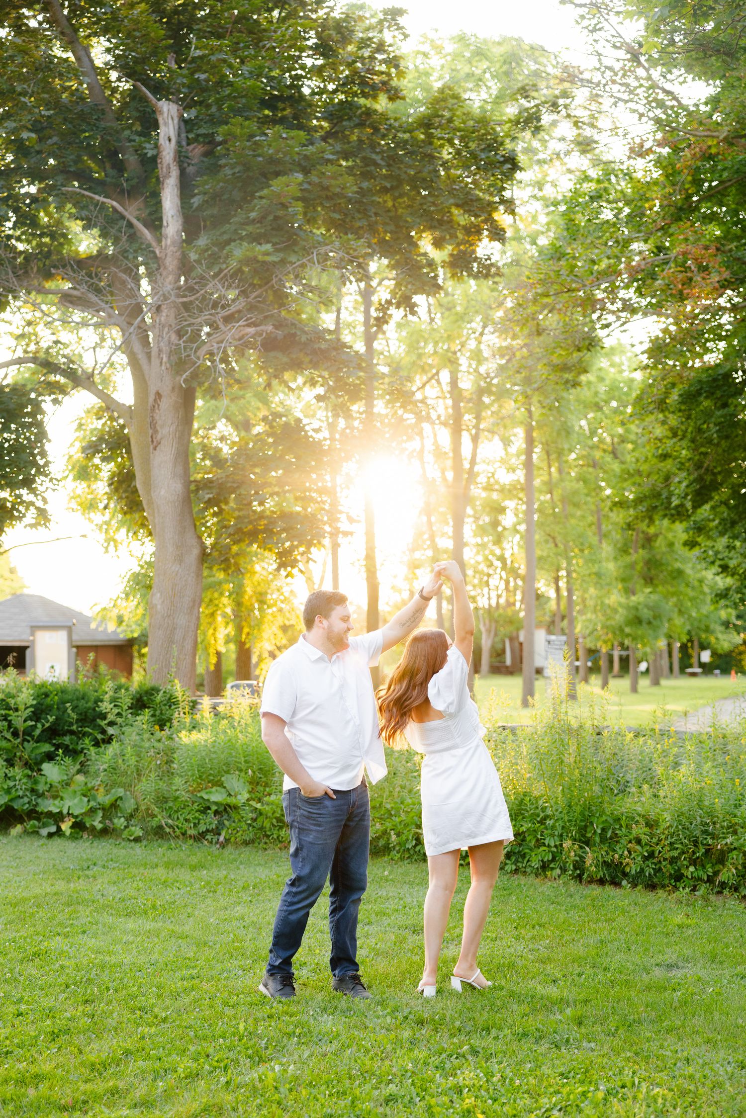 Couple enjoying a carefree moment in garden with beautiful sunset lighting.