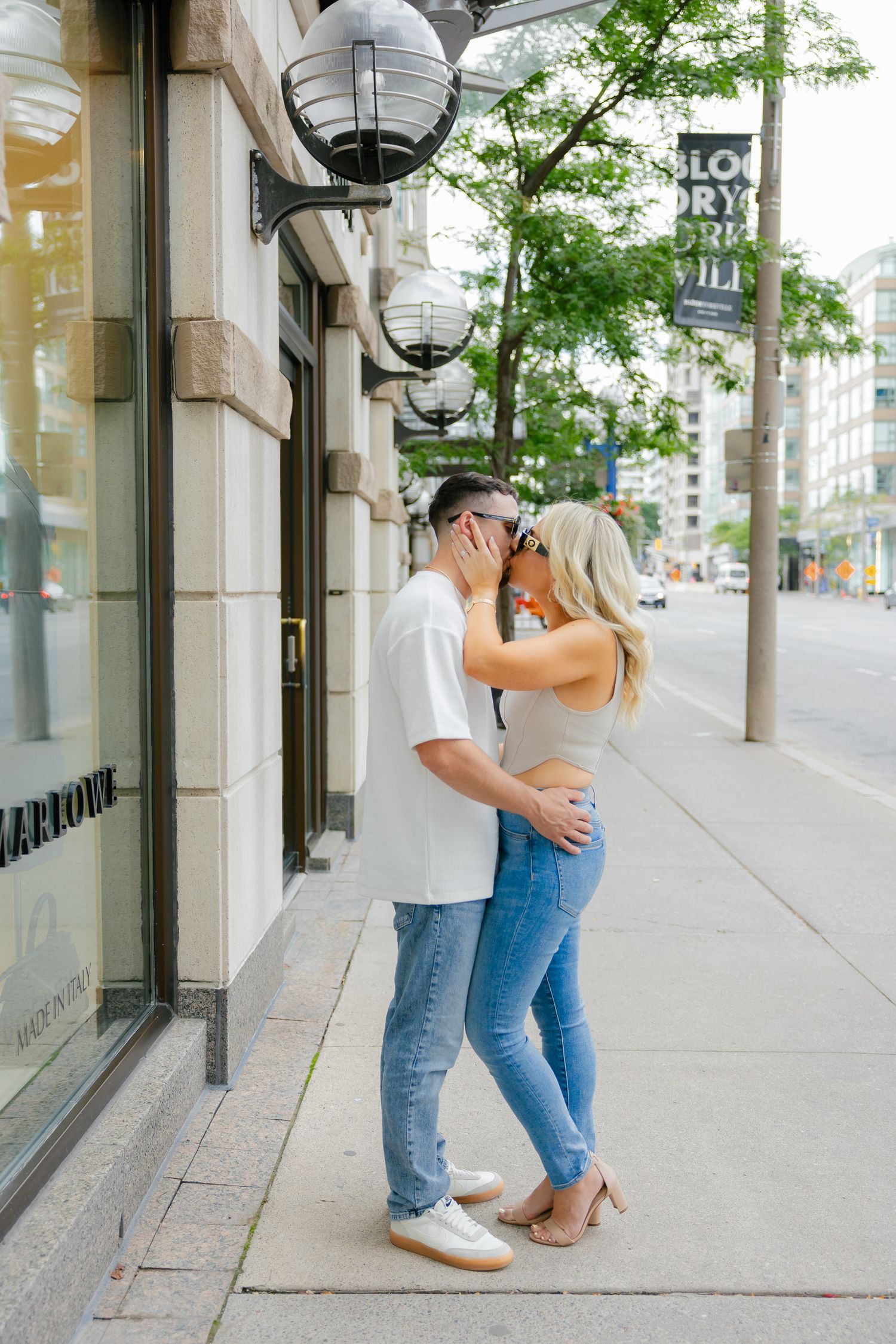 A couple in matching denim sharing a tender moment on an urban street.