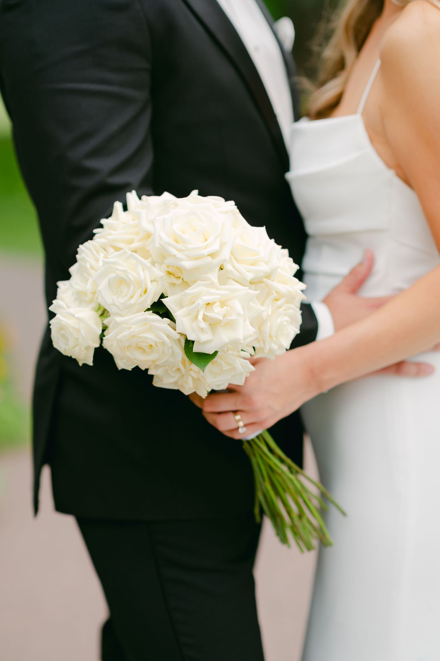 Beautiful white rose wedding bouquet held between bride and groom.