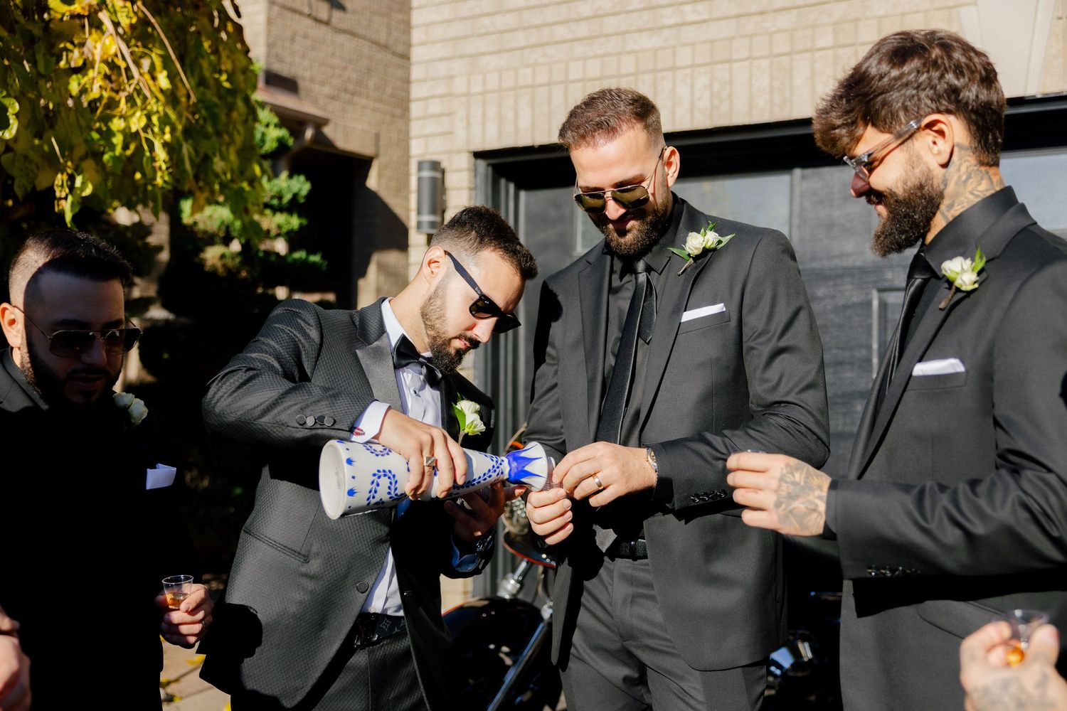 A group in dark suits sharing drinks together at an outdoor celebration.