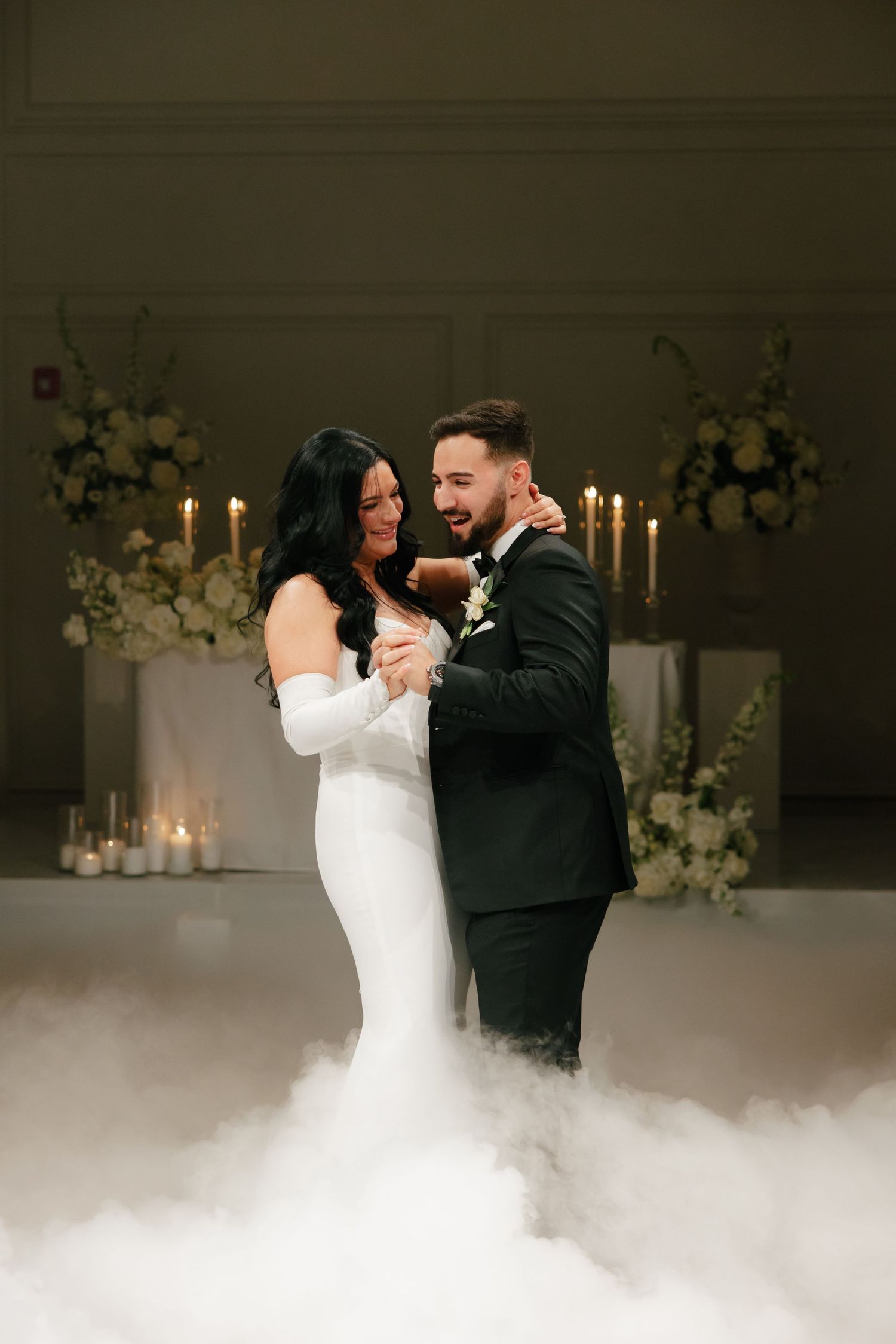 Romantic wedding dance captured with soft lighting, fog effects, and elegant floral arrangements.