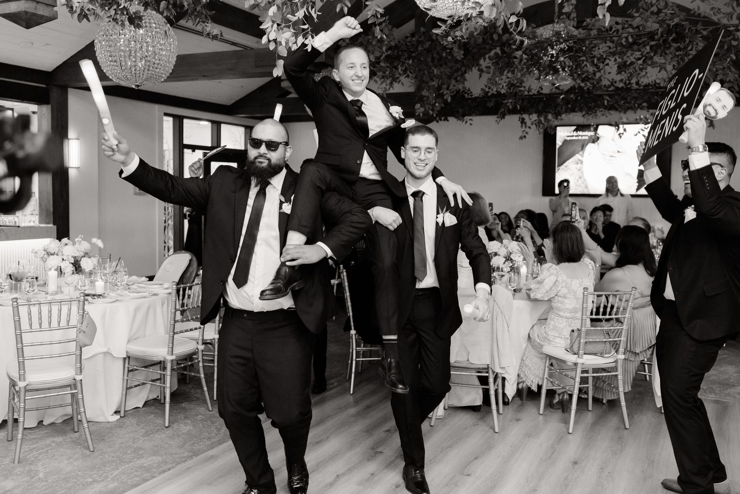 Celebratory dance scene at wedding reception in black and white photography.