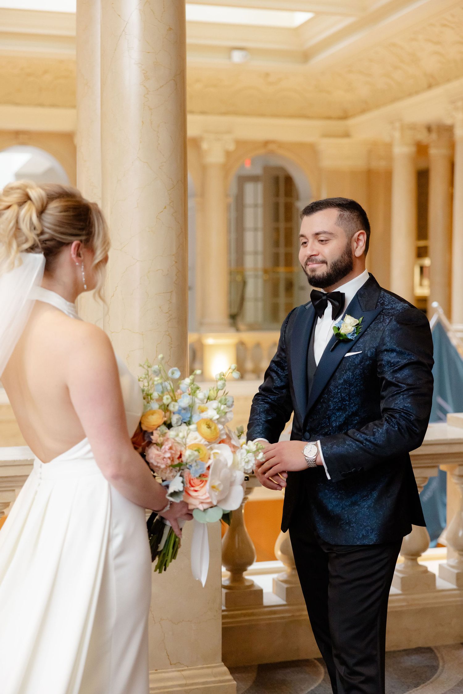 First look sequence in elegant venue with columns showing couple's emotional reaction.